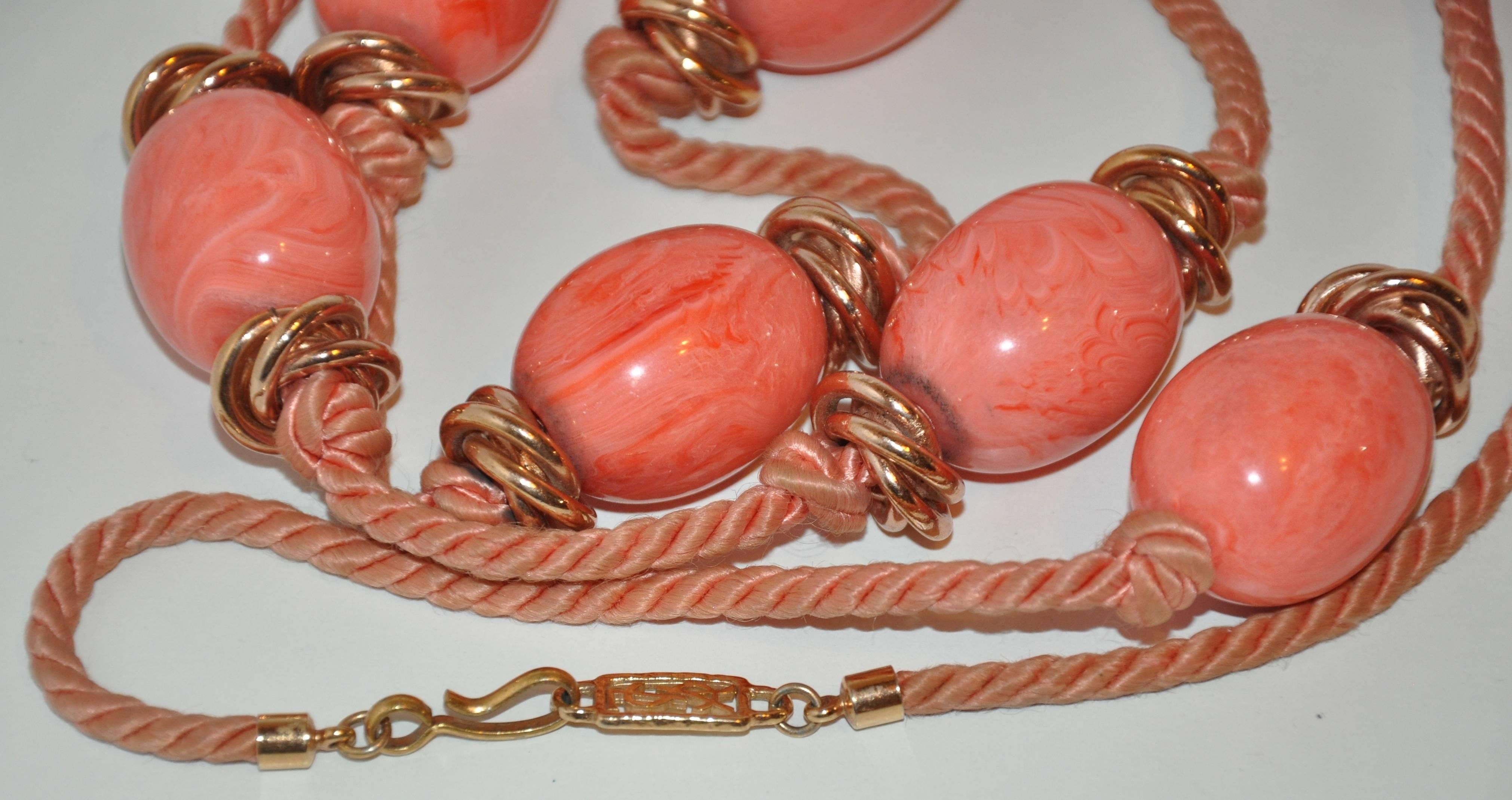         Yves Saint Laurent wonderful coral lucite accented with gold hardware on silk cord necklace measures 48" in total length and 1" in width and depth. The clasp "hook" is highlighted with his signature YSL logo.