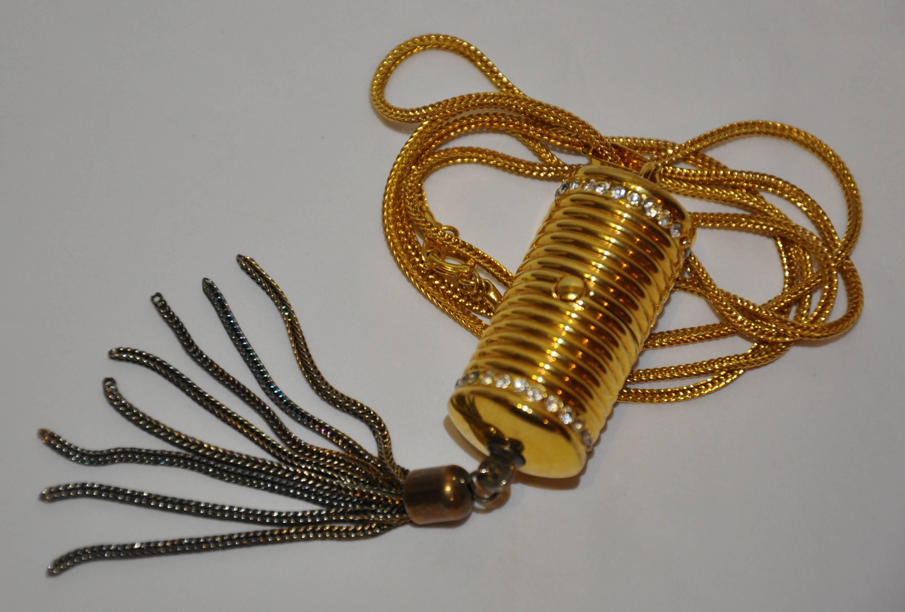       This simply yet elegant gold tone necklace is accented with a navel "weight" highlighted with two rows of rhinestones and finished with a dangling tassel. The necklace measures 30" in length. Pendant measures 4 1/2" in