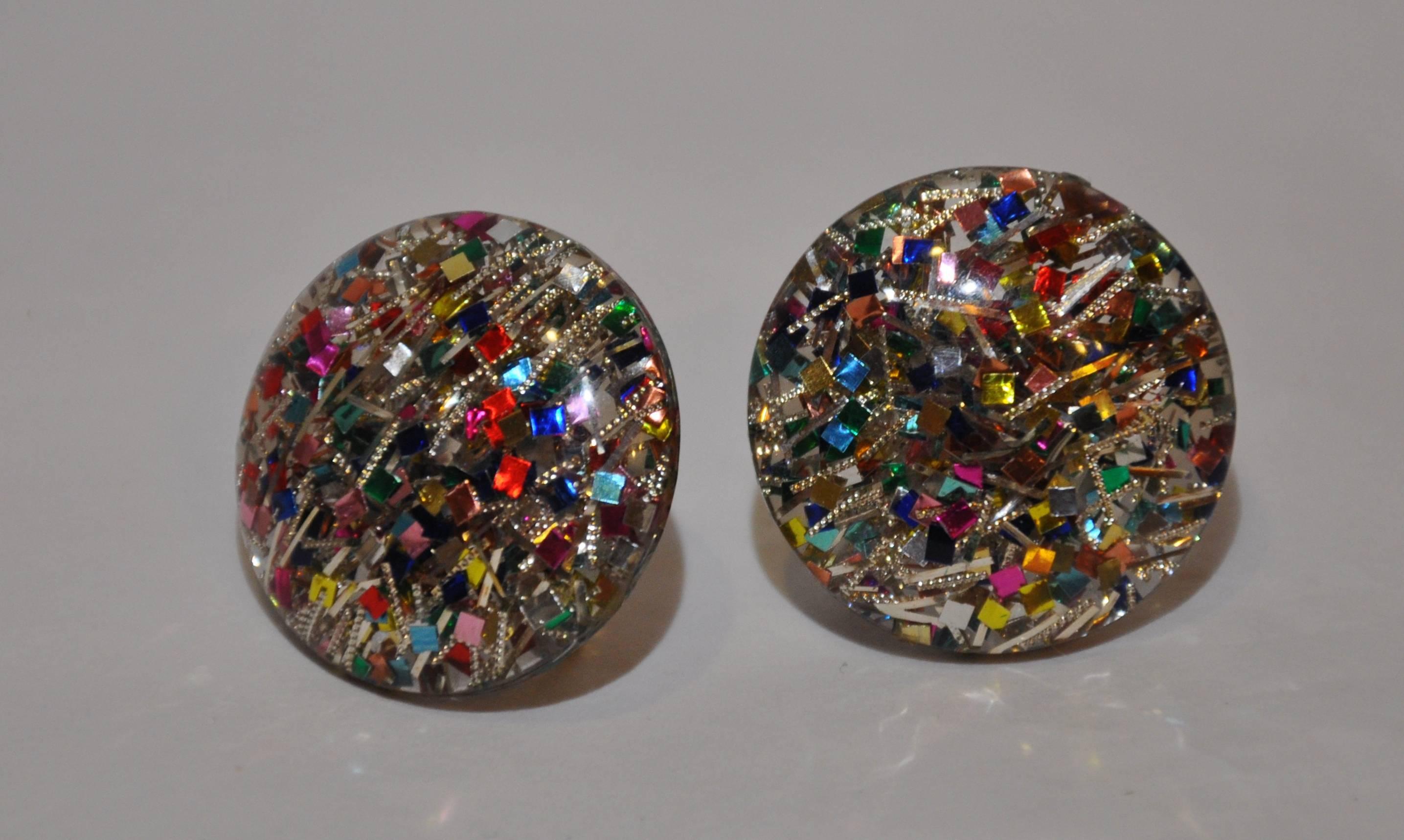          Large clear lucite screw-back earrings are accented with multi-colors of "confetti" wonderfully blended within. The width and length measures 1 1/8". The depth measures 1/2".