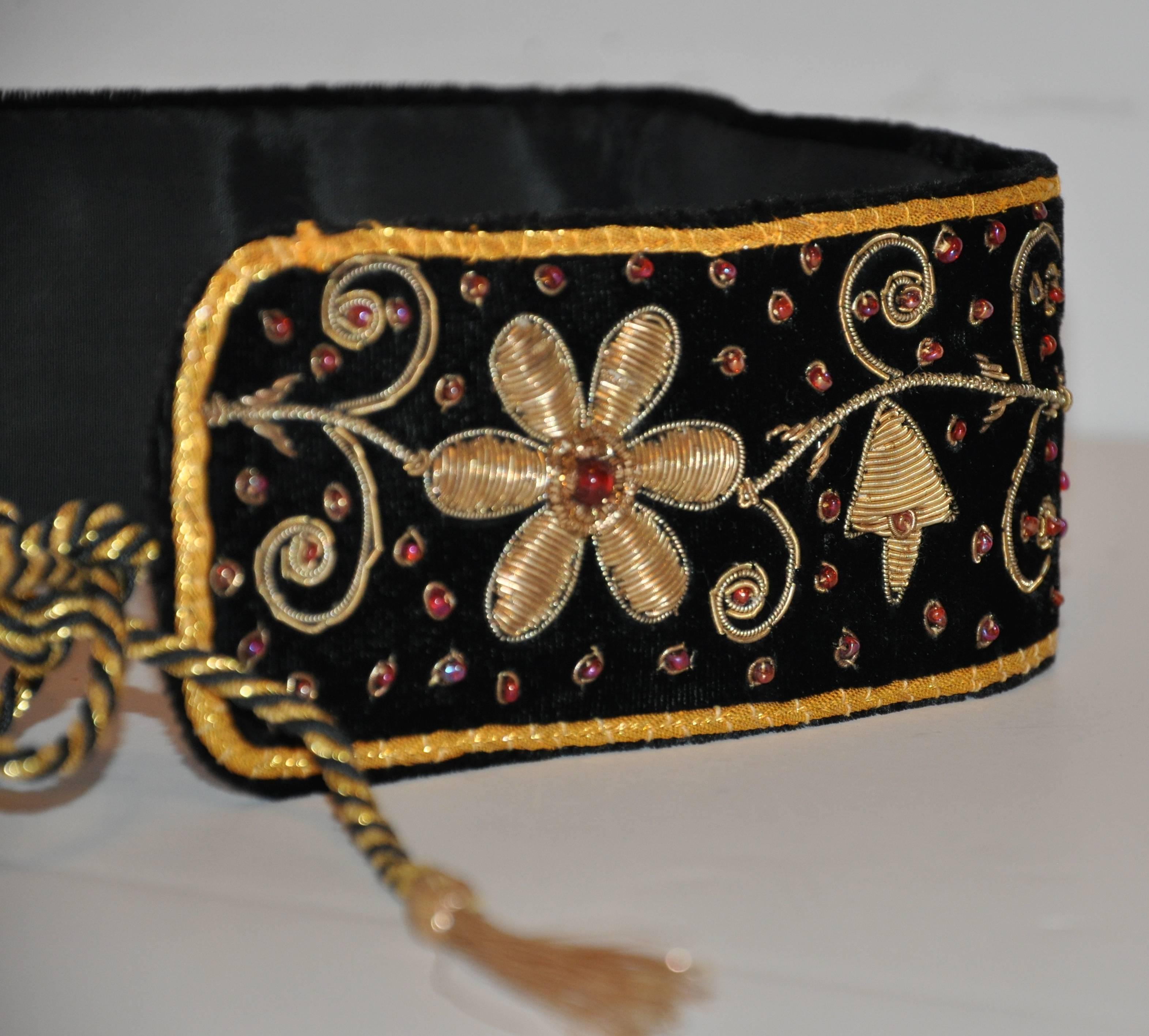        Mary McFadden wonderfully hand-made elegant evening black velvet belt is  detailed in a floral design combining semi-precious stones with gold threading. The edges are finished with hand-braided gold thread cord as well as with the tie which
