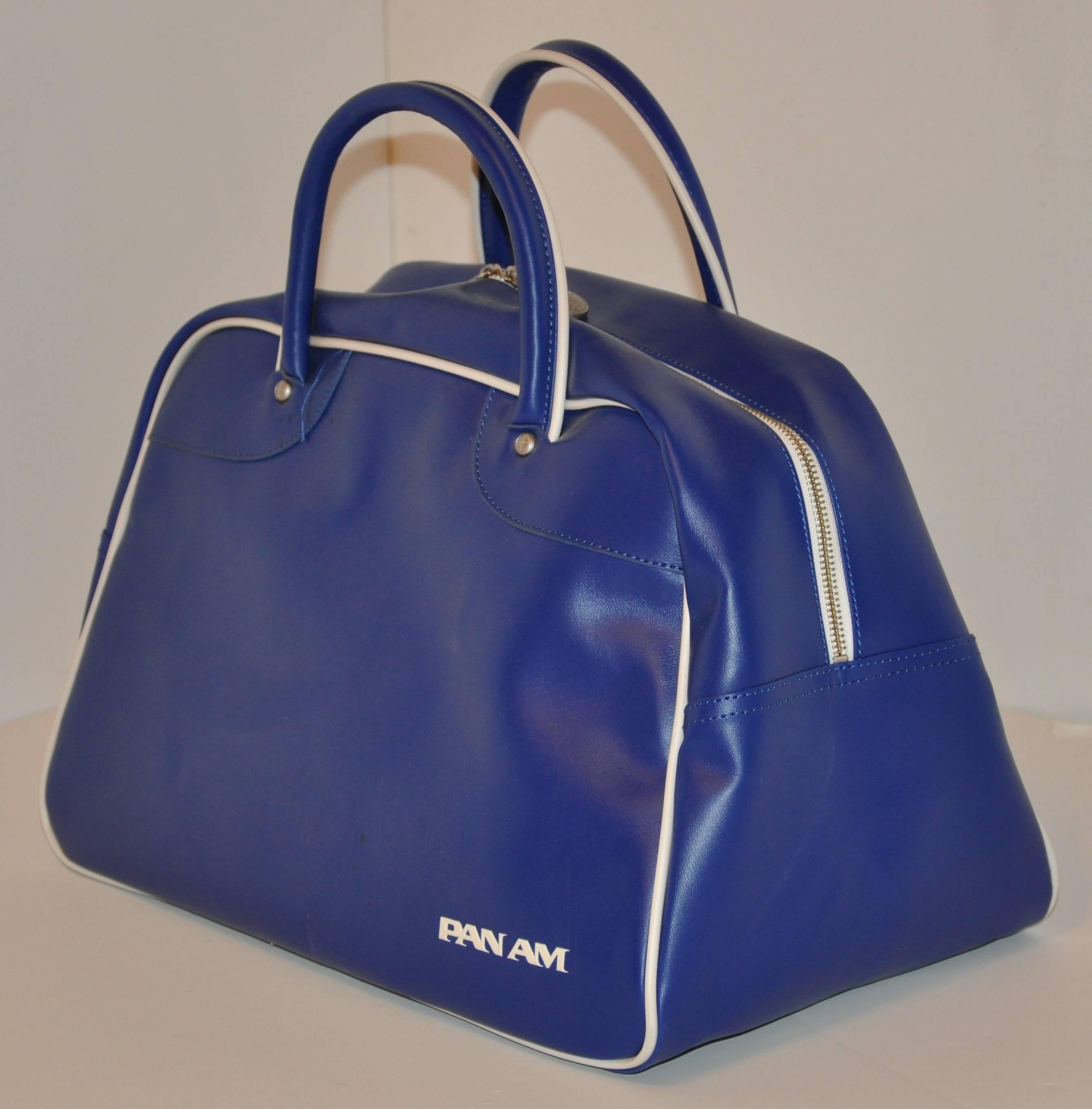        Pan Am's iconic signature navy & white zipper top travel tote is detailed with silver hardware studs engraved with their logo on all four ends of the double handles as well as silver hardware tabs with their 