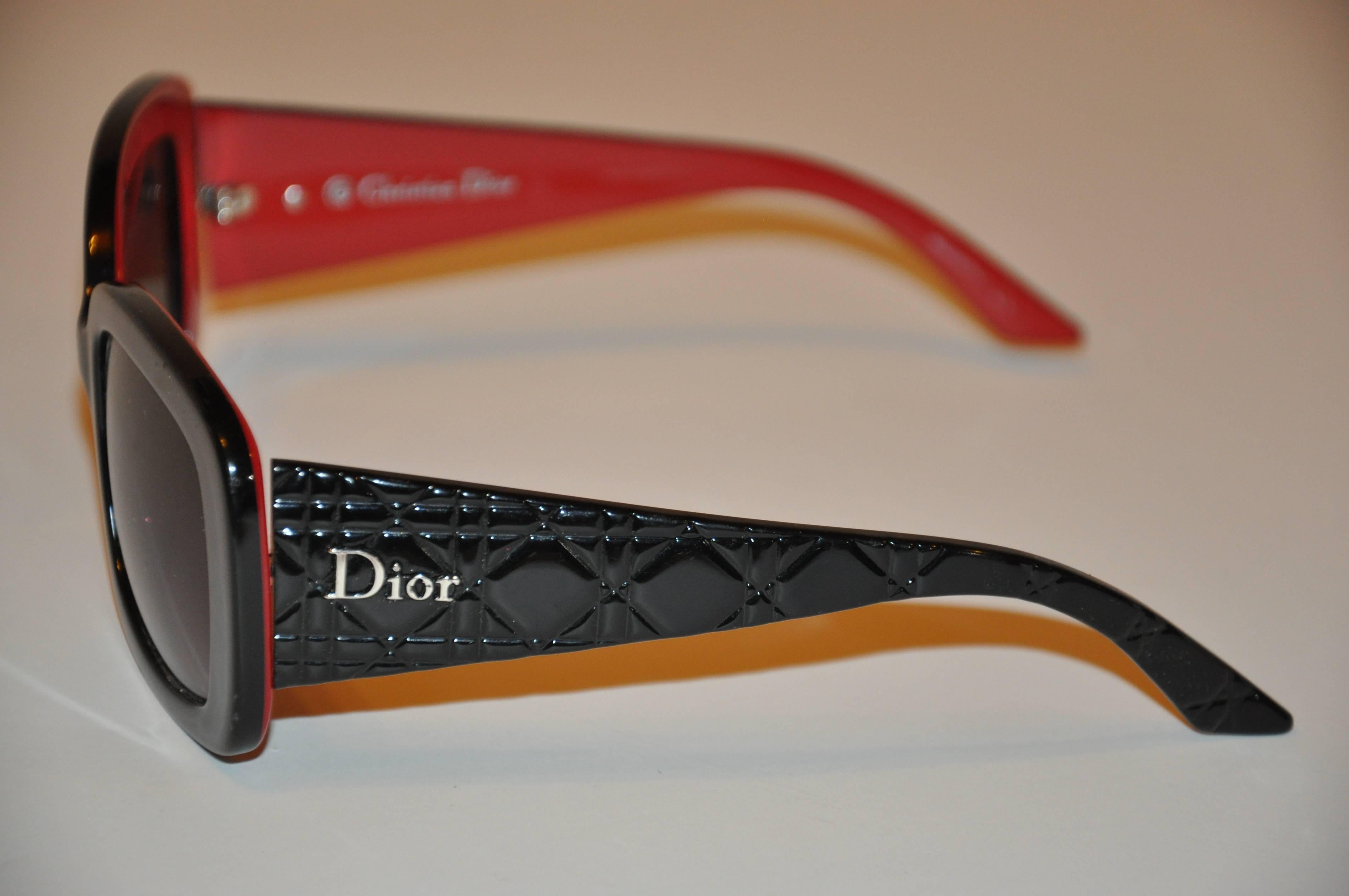        Christian Dior thick black lucite sunglasses are accented with lucite interior in brick color.  The sides are accented with detailed quilting. The width across the front measures 5 3/4