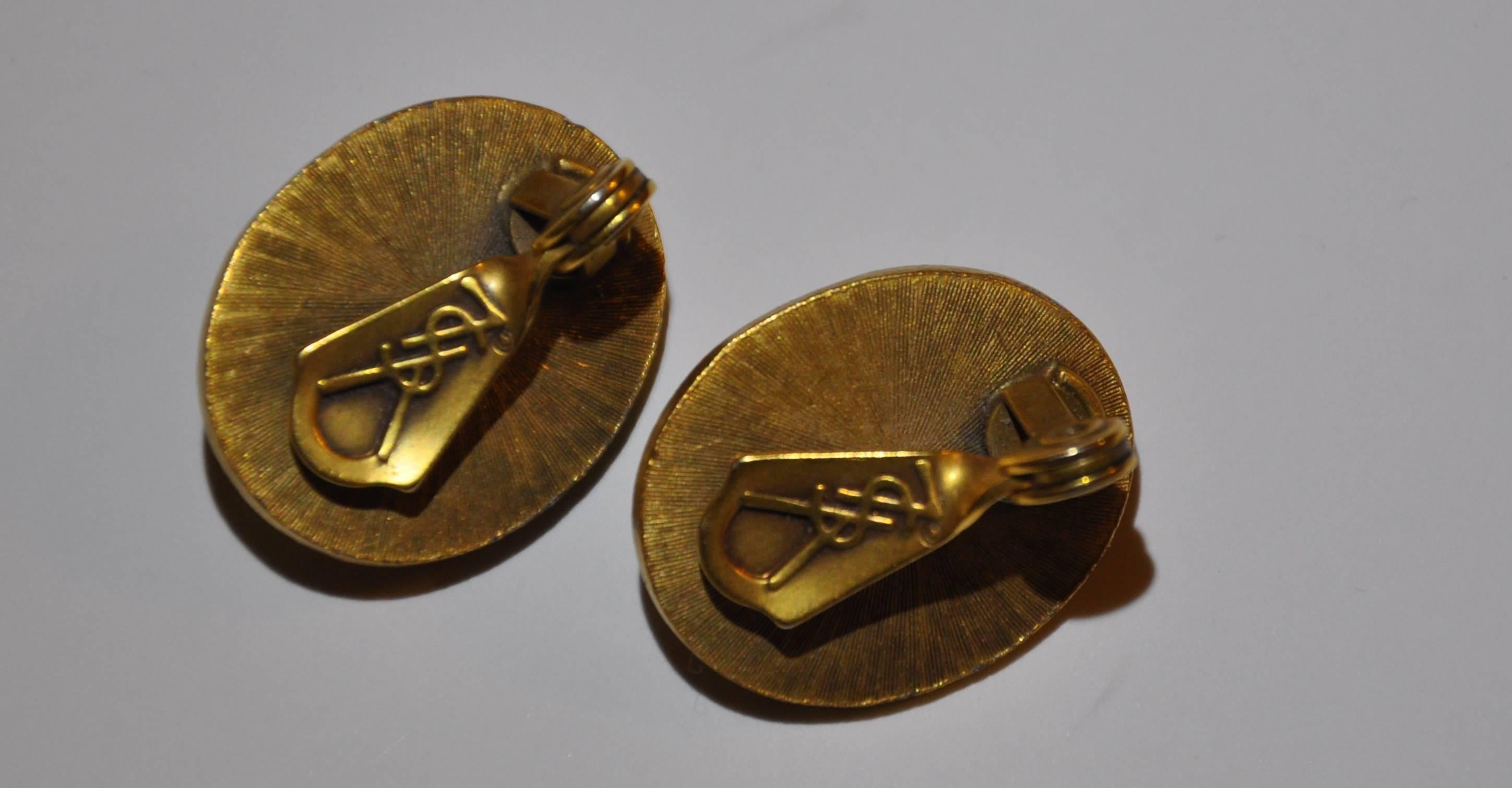 Les boucles d'oreilles clip Yves Saint Laurent, merveilleusement élégantes, en ton or, sont détaillées avec un design de 