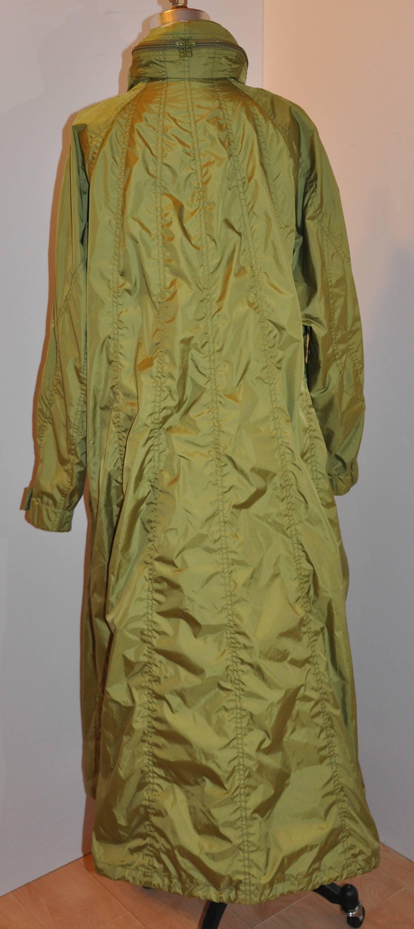 Issey Miyake 'Fete' wonderfully detailed olive green maxi nylon trench coat has a optional hood, which can be adjusted when used, neatly tucked into the collar closed with two zippers when needed. Hemline has a optional drawstring to create a