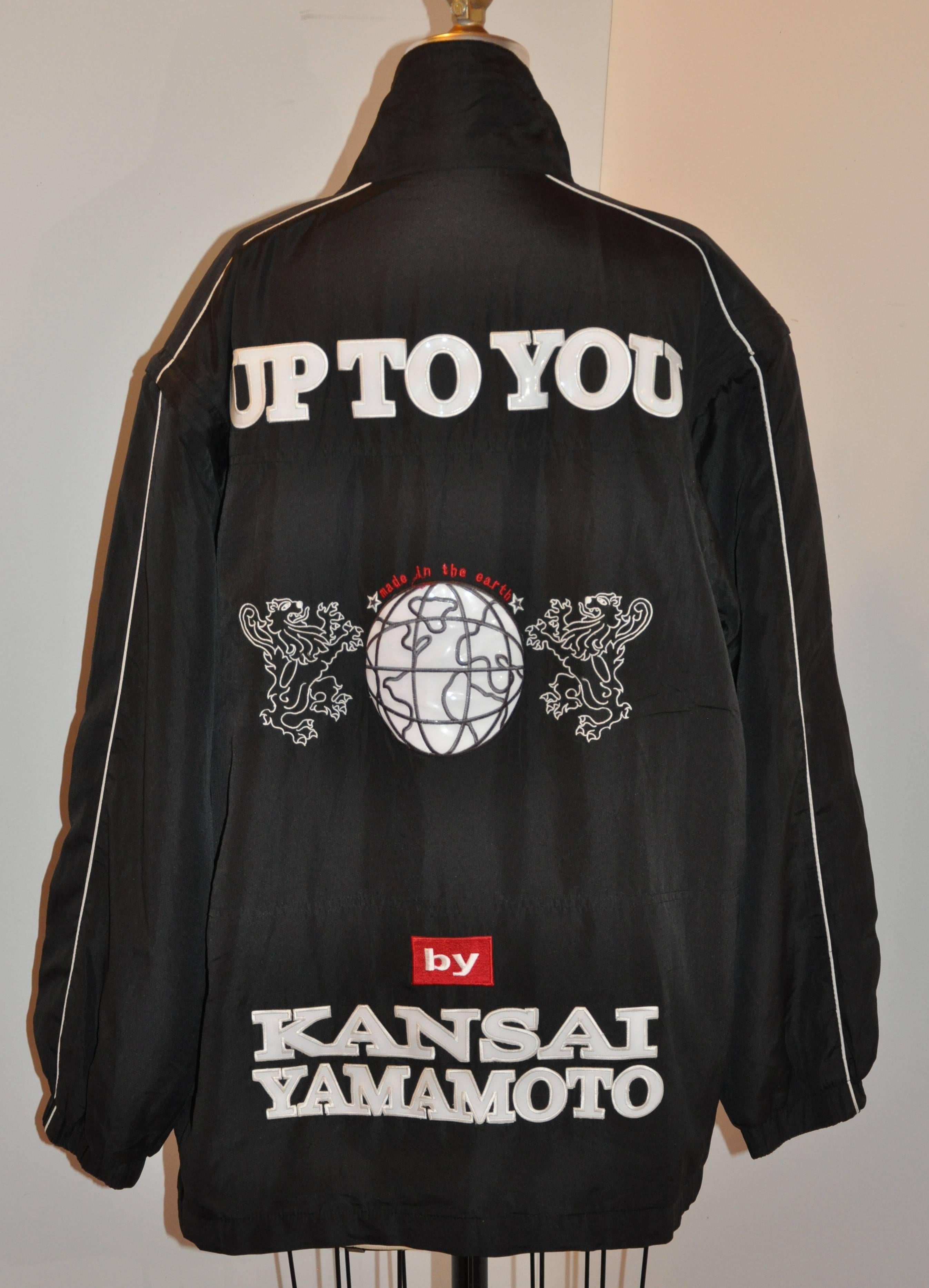 Kansai Yamamoto Men's black nylon zippered "Up To You" embroidered jacket is detailed with patches of "Up To You" in bold patches on the backside. The front bottom near the hem is accented with a rubber embossed patch "Up To