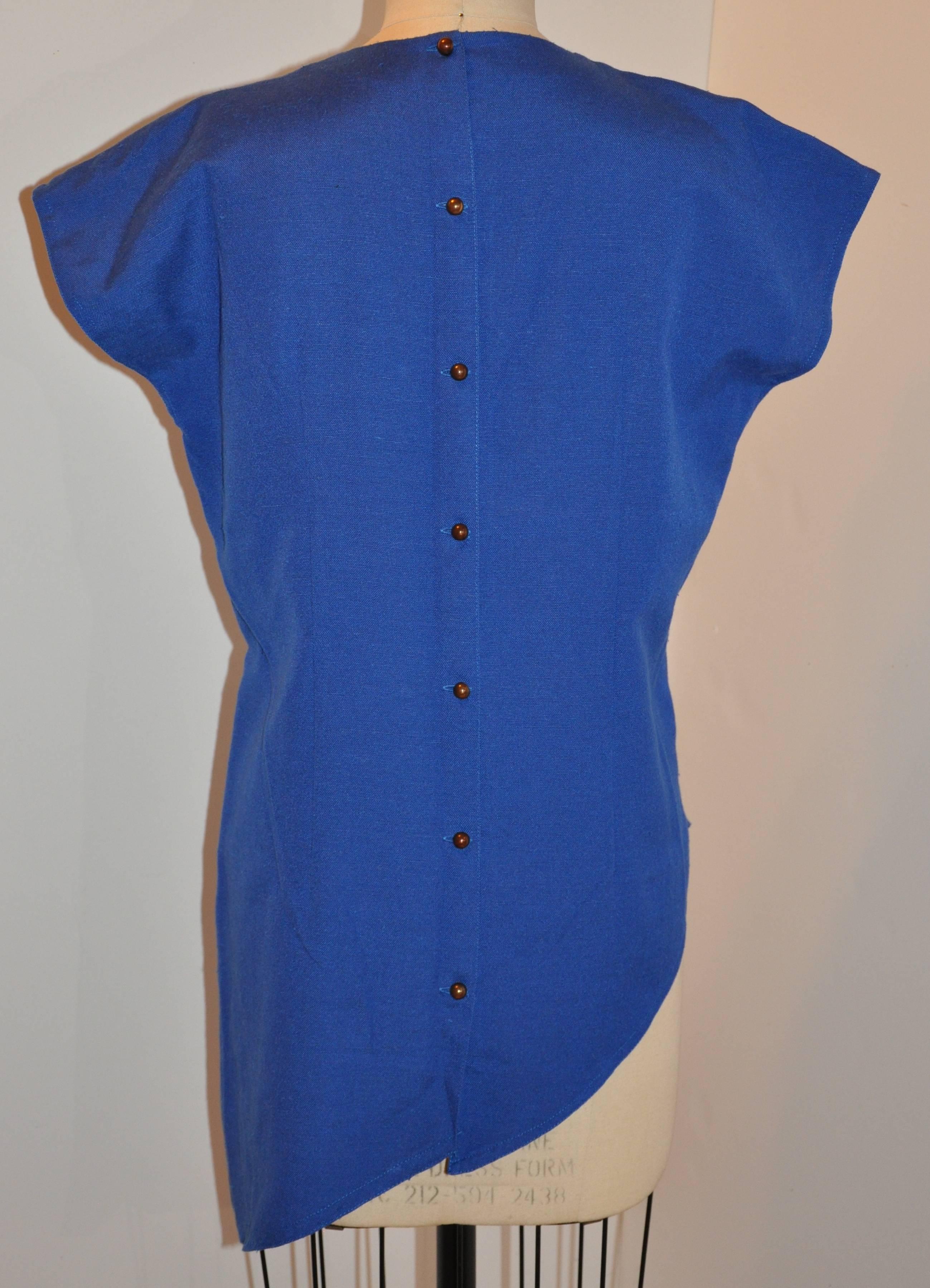 This wonderfully detailed asymmetric blue tunic is accented with gold lame and eyelet embroidered detailing. The center back has seven(7) small round brass buttons. The length measures from 32" - 30" - 21", with underarm circumference