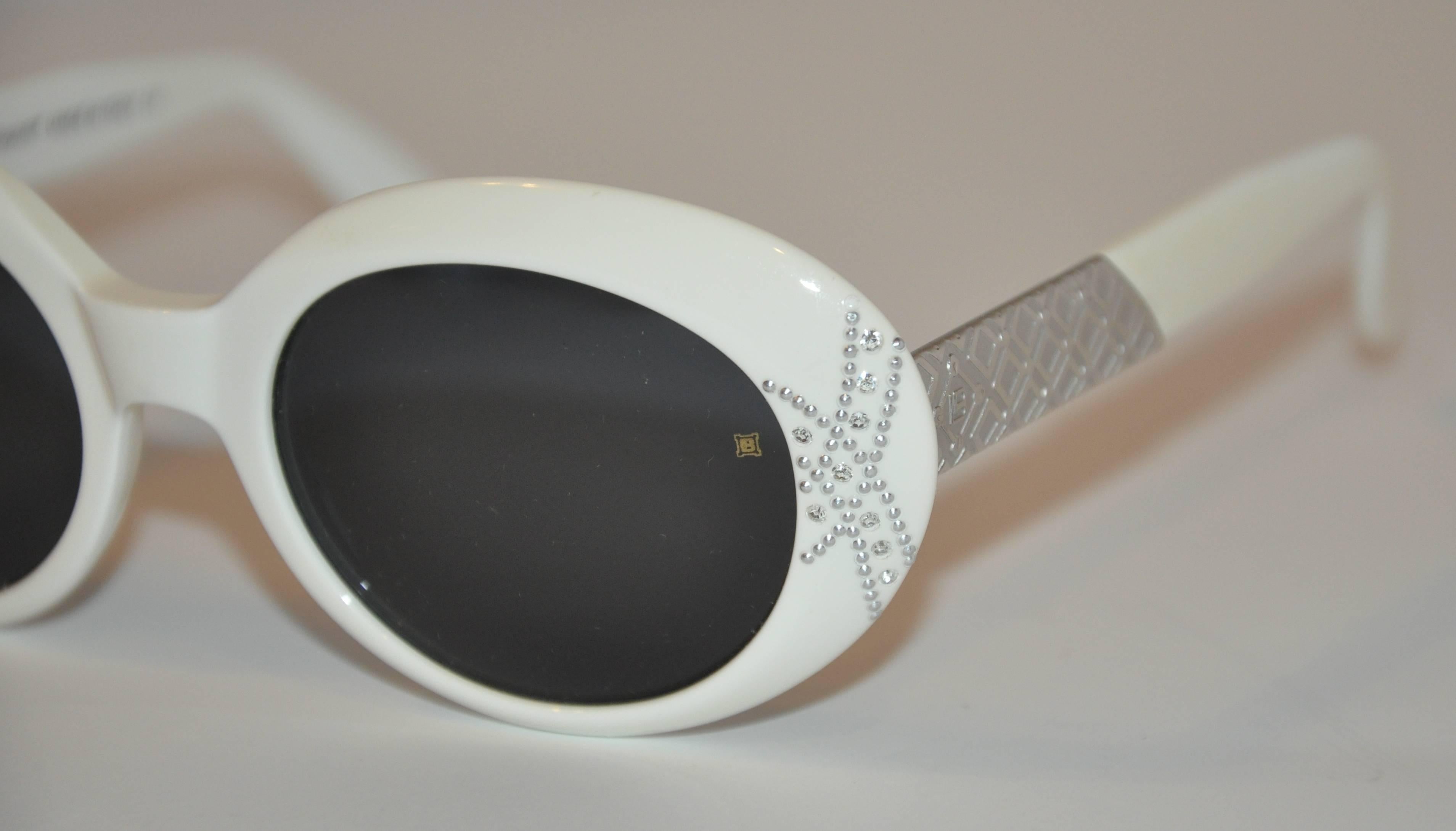 Laura Biagiotti wonderful dark shades with white round frames are detailed with brushed silver engraved hardware as well as micro studs and rhinestones near the corners on the front. Sides are carefully detailed with criss-crossed engraved  squares