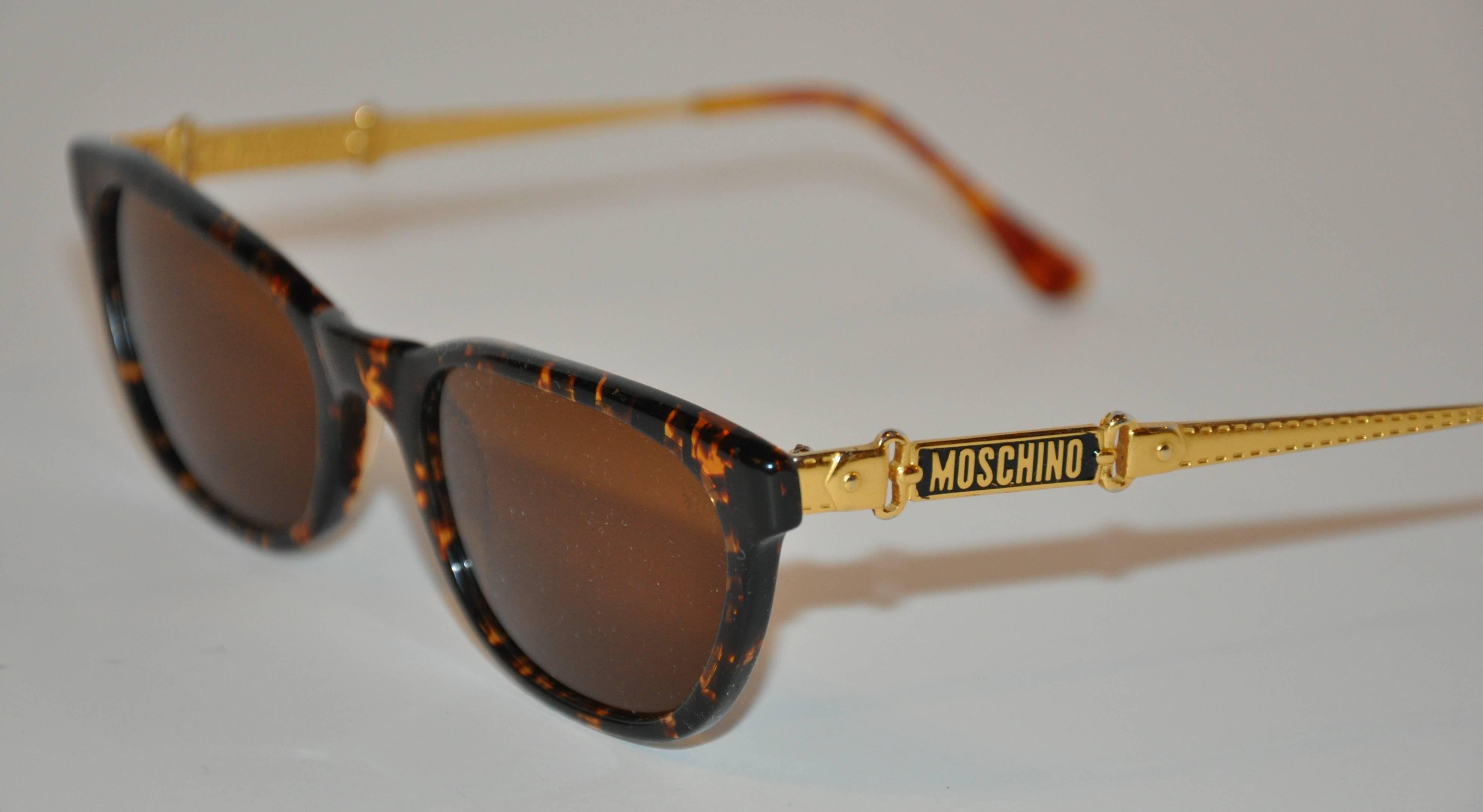 Moschino wonderfully detailed tortoise shell sunglass are engraved with the signature name-plate on both the exterior as well as the interior of both arms. The arms are also detailed with gold-tone engraved buckle and belt accents. The front
