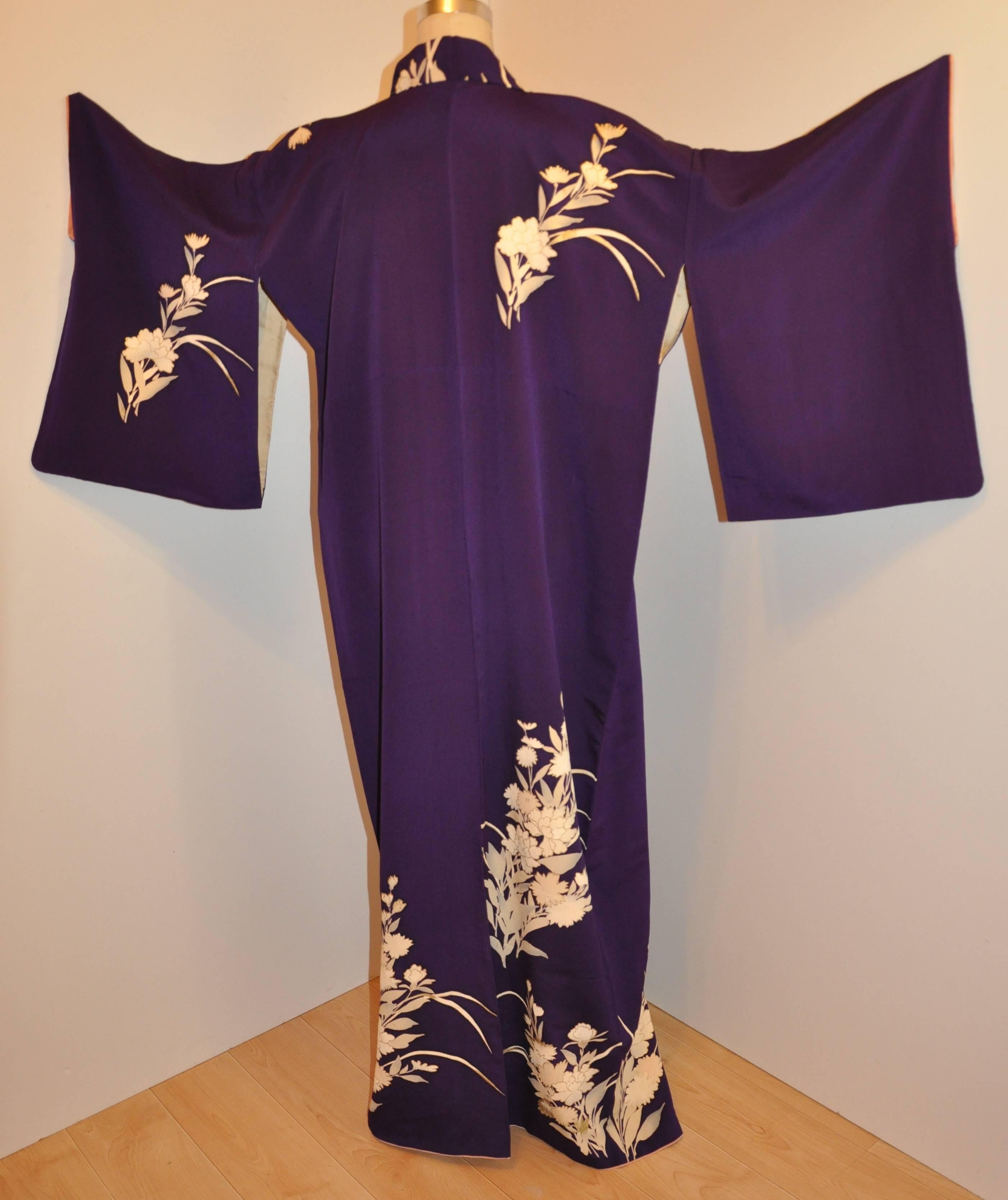        Dieser wundervoll detaillierte violette Seidenkimono ist mit cremefarbenen Blumen verziert und mit einer goldenen Metallic-Ätzung versehen, die einige der Blumen hervorhebt. Die Länge beträgt 59