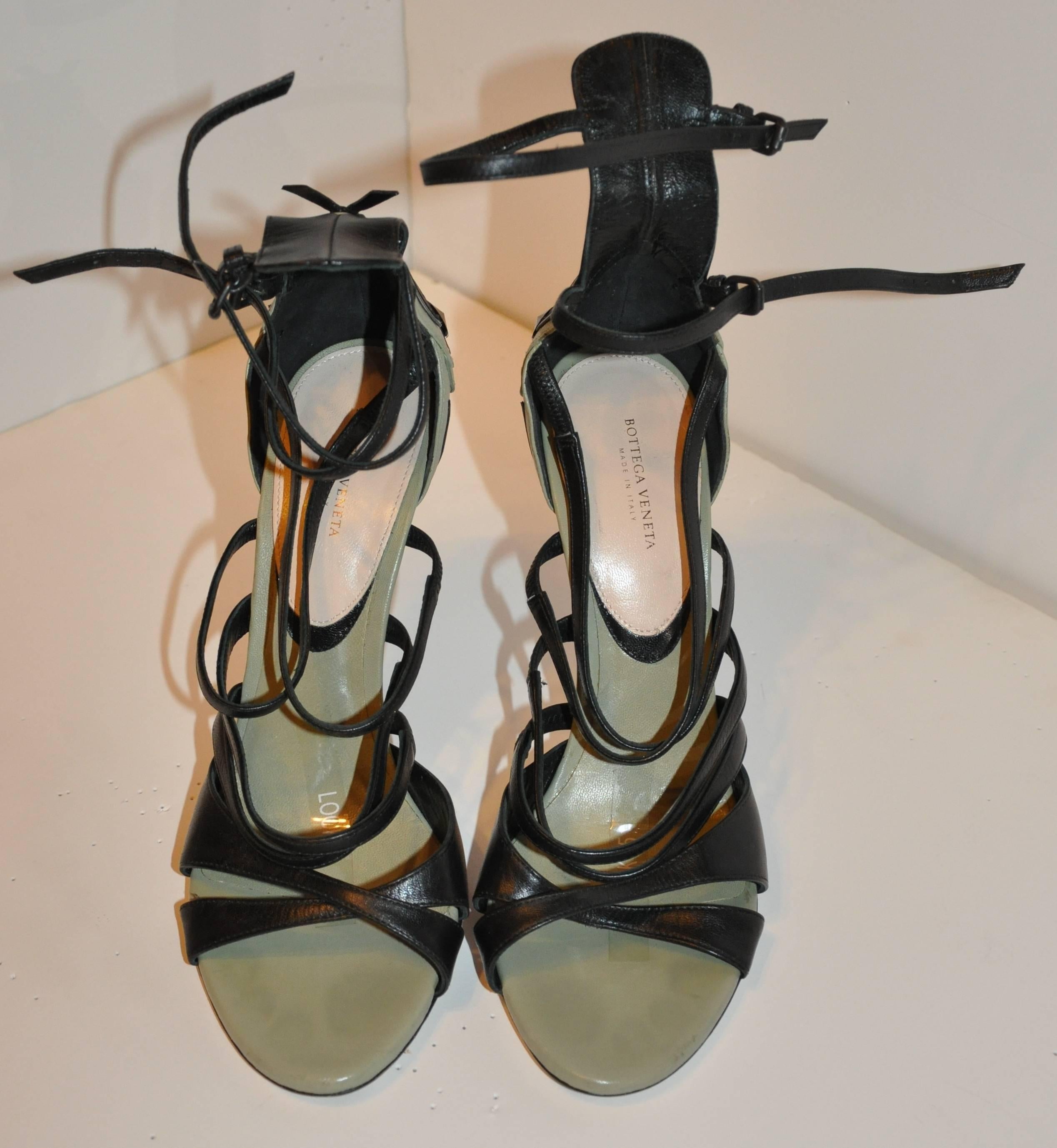        These wonderfully wicked yet elegant Bottega Veneta "Limited Edition" olive and black calfskin strappy ankle-strap heels are accented with metallic silver calfskin on the back of the heel as well as two polished black rhinestones