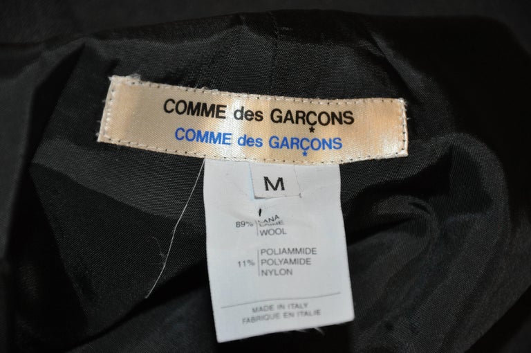        Comme des Garcons 'Comme des Garcons' charcoal spring wool velcose front closing tabs jacket/shirt is accented with domain sleeves and a mandarin collar. The sides has two slits measuring 6 1/2", as well as a center-back slit which