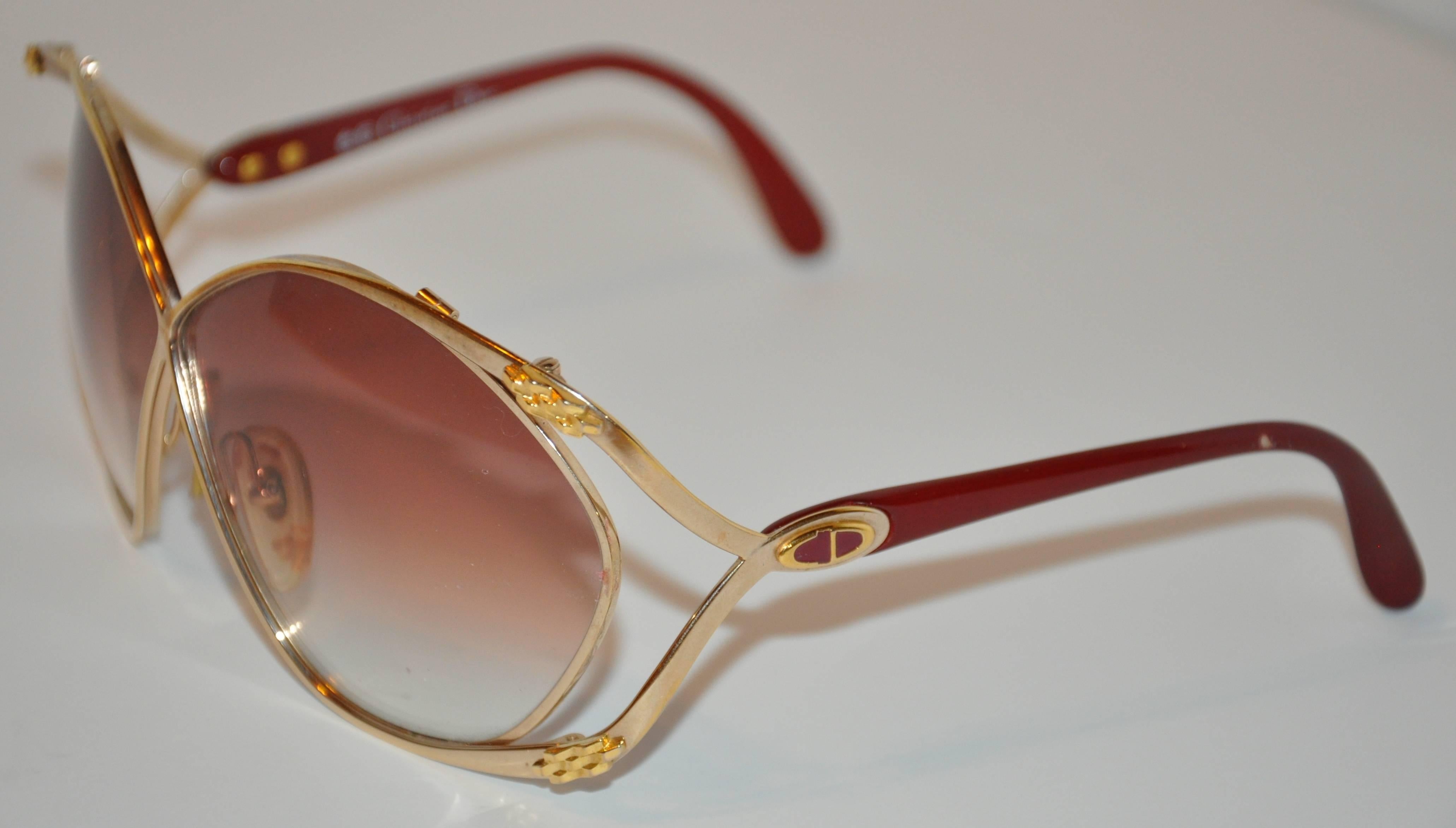        Christian Dior huge polished gold hardware frames are accented with "Chain-Links" on the front corners. The arms are curved into a single arm and finished with burgundy lucite along the tips. Their signature "CD"