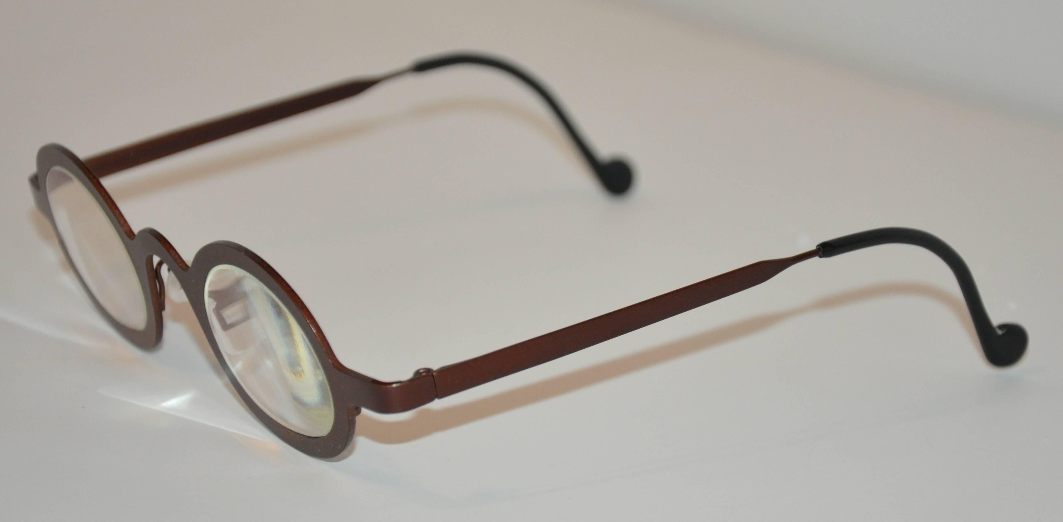        Theo (Belgium) "Keith" steel-bronze prescription glasses measures 5 3/8" in length across the front. The height measures 1 9/16", arms are 5 3/8" accented with black lucite. Made in Belgium.