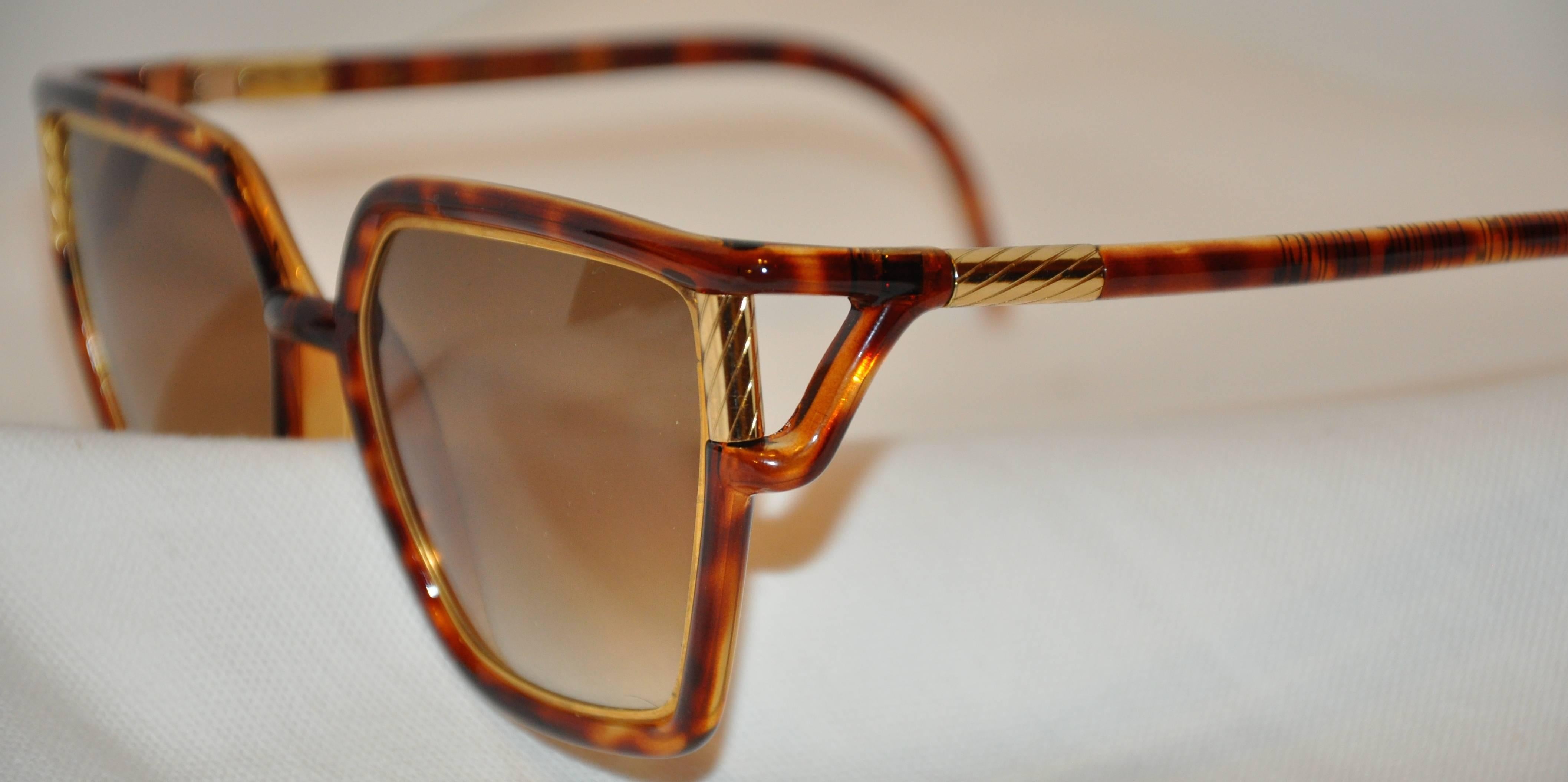        Ted Lapidus wonderfully large tortoise shell sunglasses are detailed with etched gilded gold hardware on both the front as well as the arms. The length across the front measures 5 3/4 inches, height is 2 1/4 inches, arms are 5 1/2 in length.