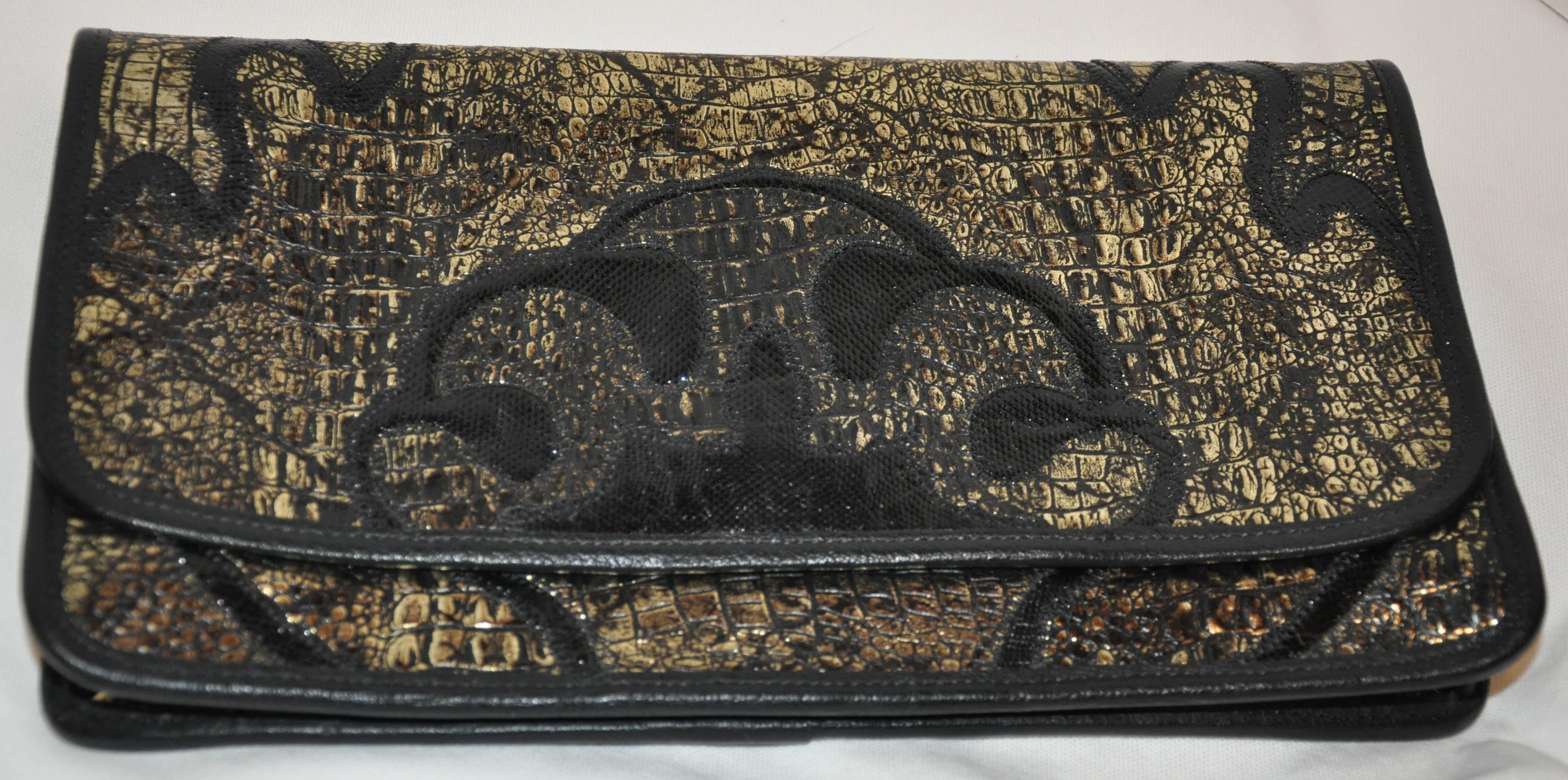        Carlos Falchi wonderful black and metallic gold embossed alligator calfskin clutch has the option to use as a shoulder bag as well if desired. Black lizard skin is detailed on both the front as well as the back. All edges are finished with