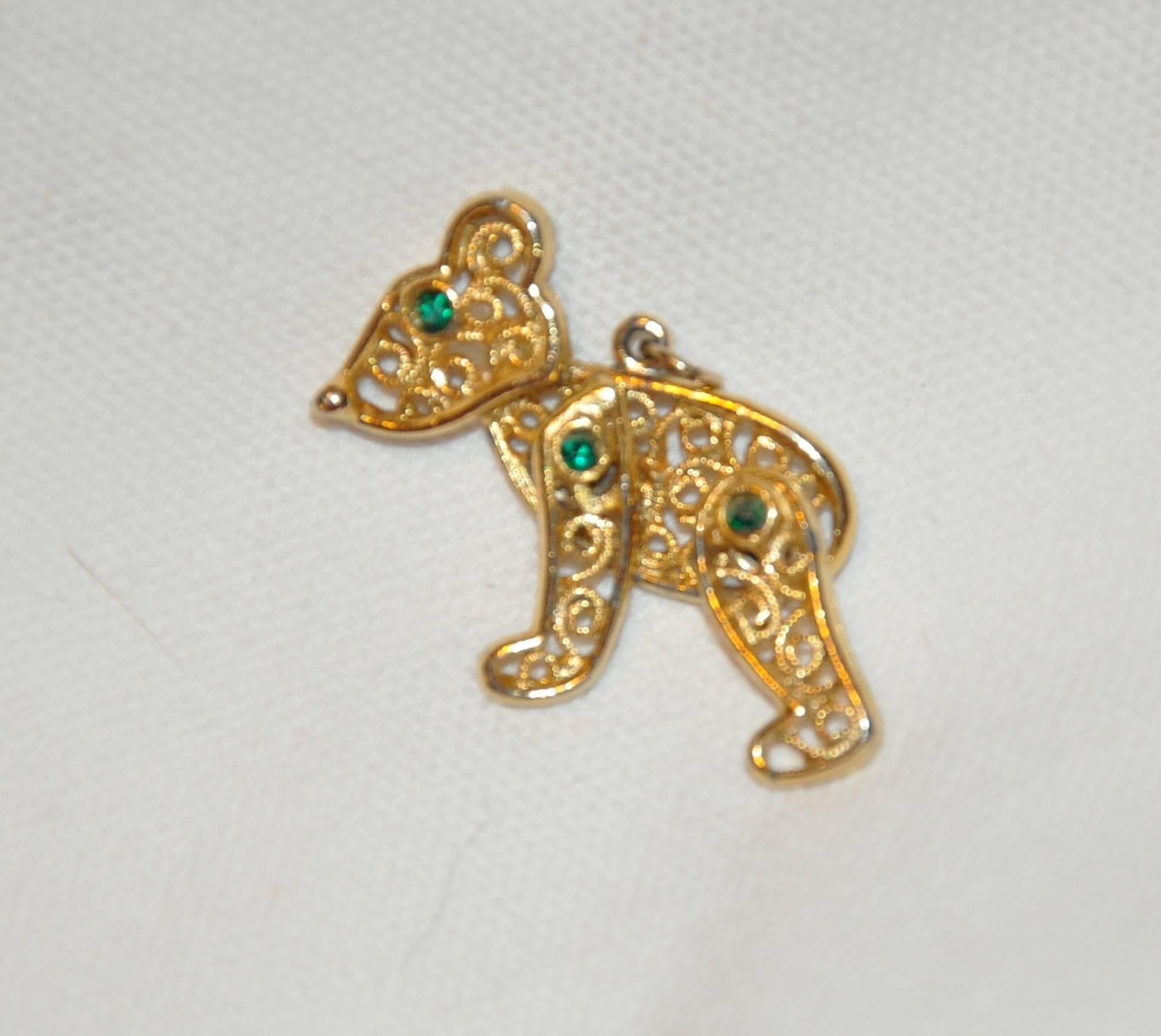        This wonderfully whimsical moveable "Teddy" pendant in gilded gold hardware accented with faux emerald eyes accented with filagree detailing measures 1 1/2 inches by 1 1/2 inches.