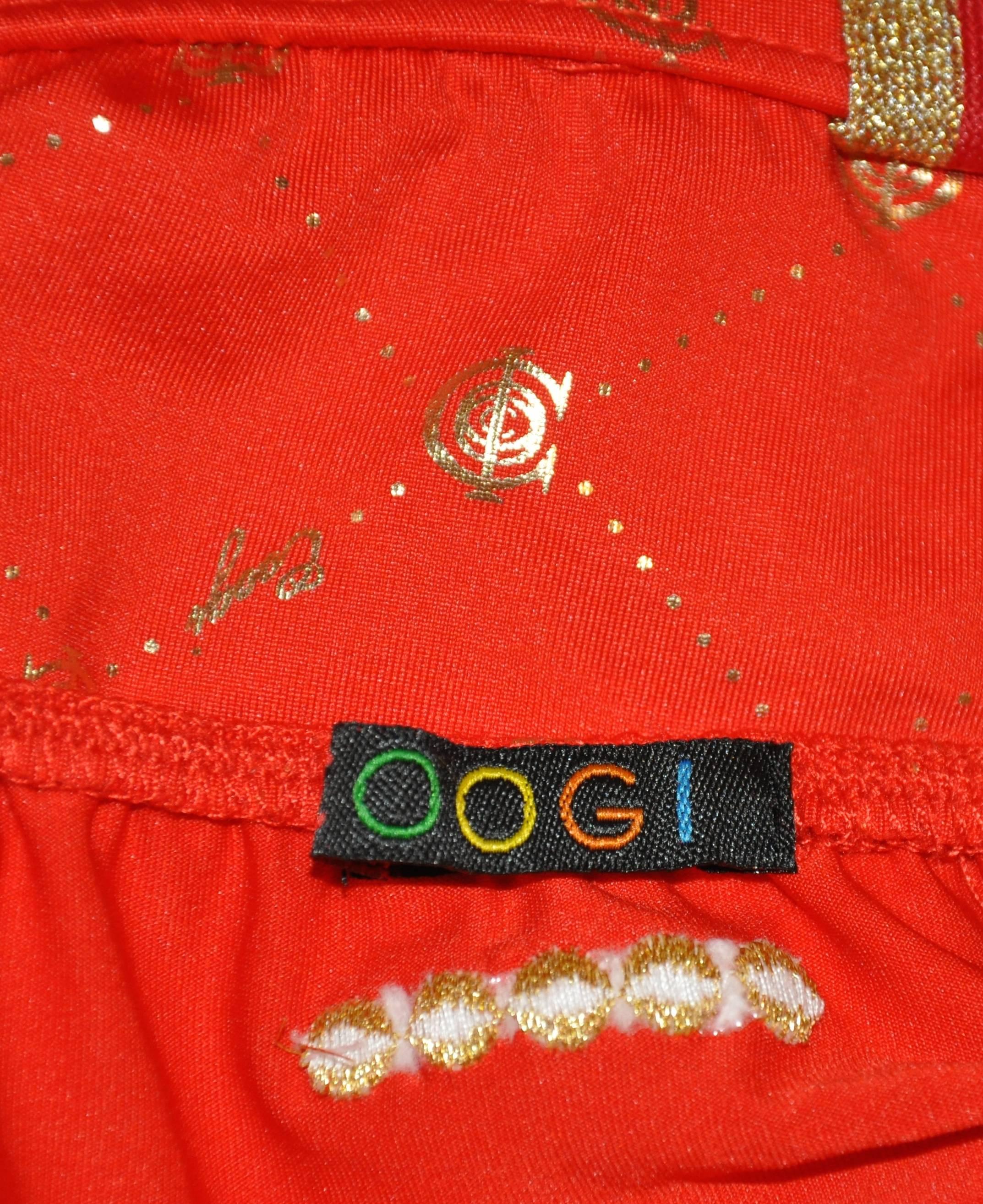        Coogi wonderfully whimsical bold red is accented with gilded gold throughout and detailed with red & metallic gold faux belt loops. The halter tie is golden beige as well as the adjustable hip ties in front. Their signature logo is