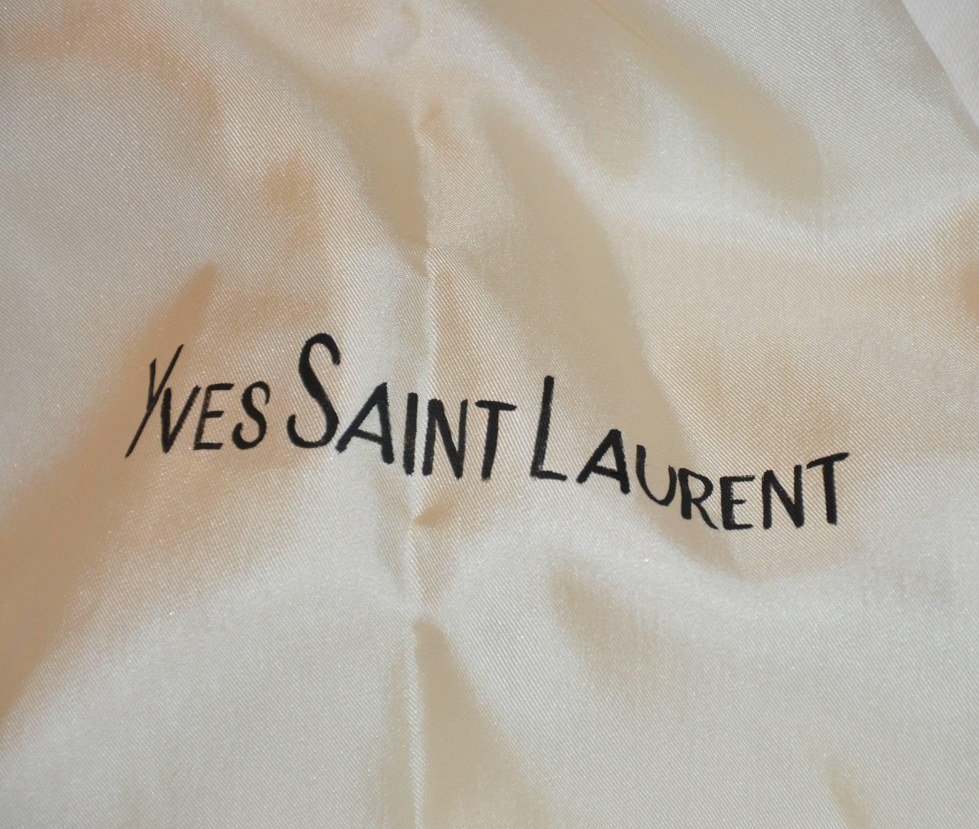    This wonderfully elegant and rare Yves saint Laurent ivory jacquard silk hand-tucked turban is accented with a extended train finished with fringed edges. His signature name is hand-painted along the train. The interior is accented with a