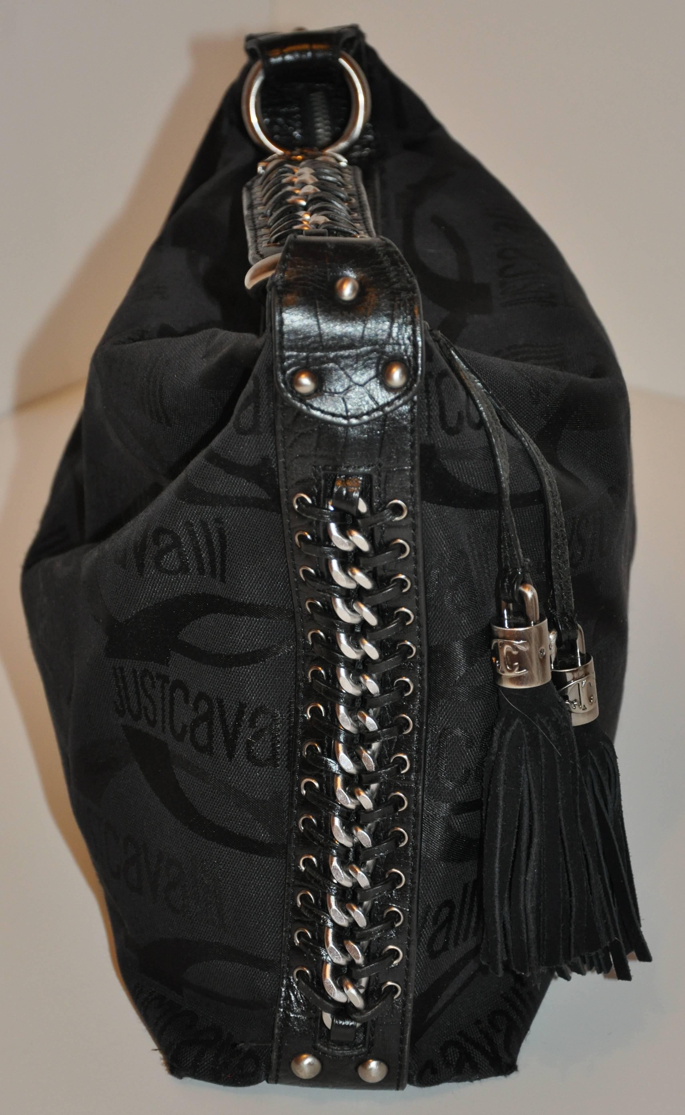       Roberto Cavalli black signature logo handbag is detailed with hand-woven sides combined with matted steel gray hardware and calfskin. The zippered top measures 14 1/2 inches, accented with two suede poms-poms along with his signature logo on