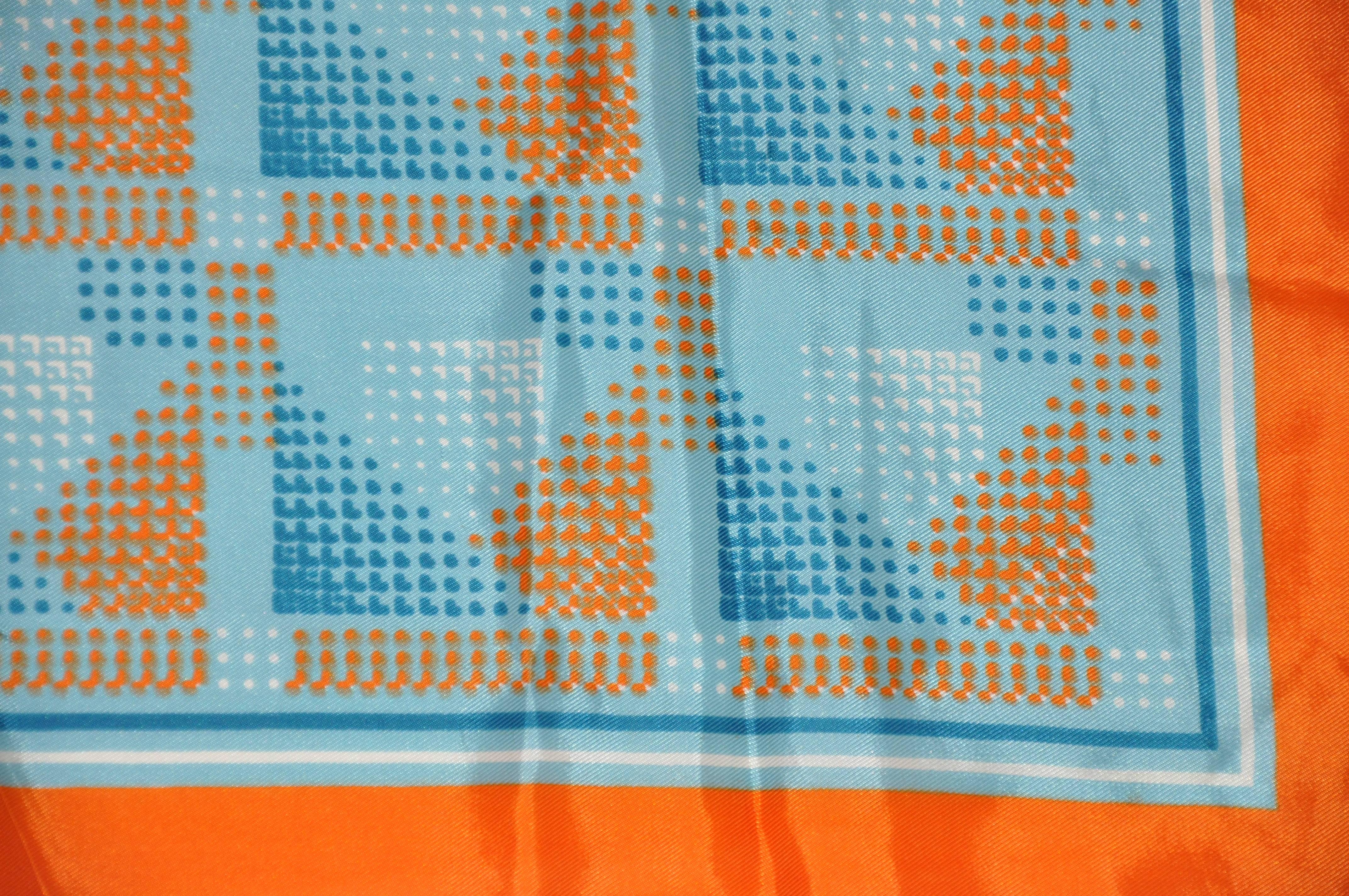        Wonderfully bold, this bold tangerine border with shades of blues & oranges abstract scarf measures 26 inches by 26 inches. Made in acetate in Japan.