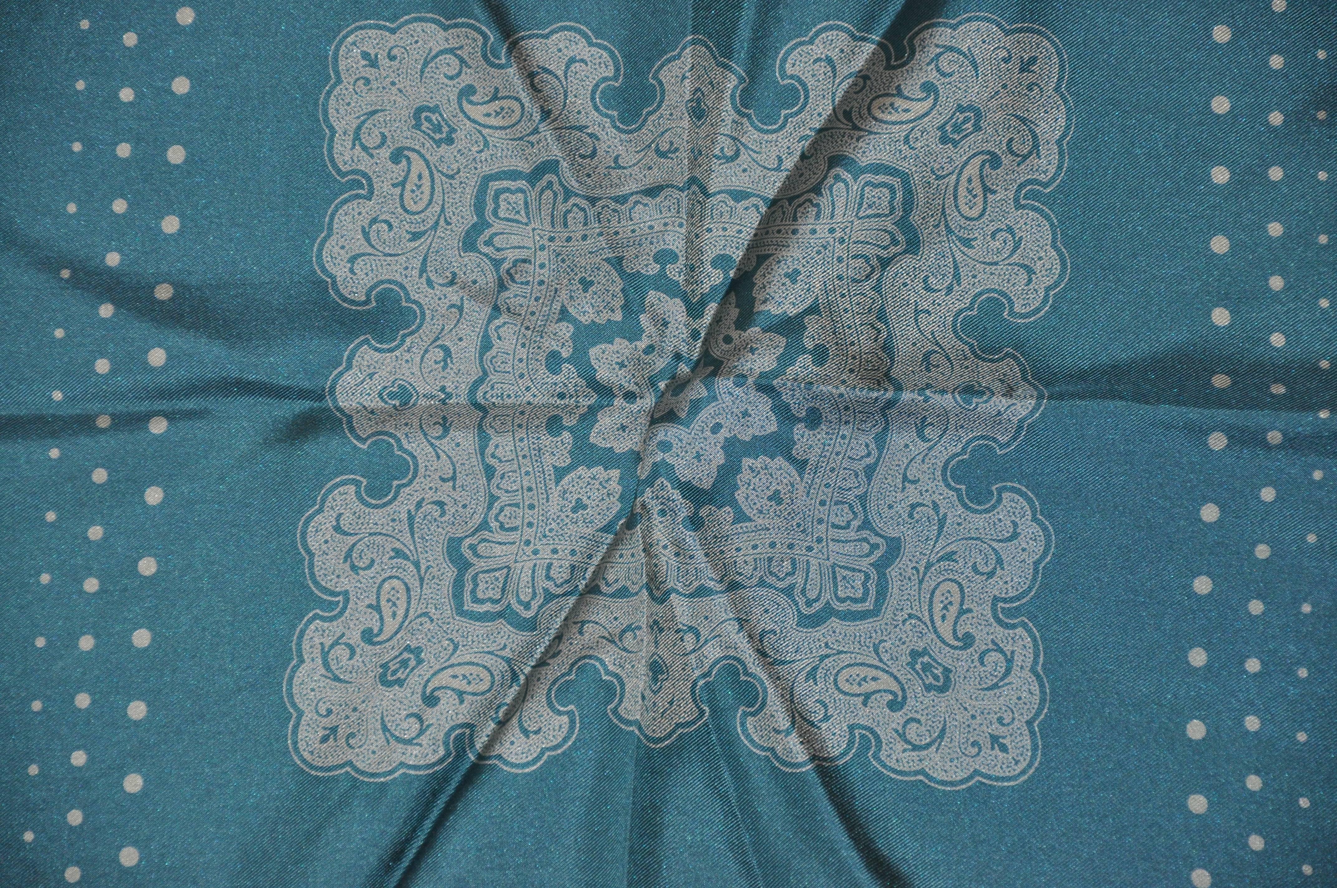       Le mouchoir en soie vert turquoise accentué du centre Palsey a des bords roulés à la main et mesure 13 pouces par 13 pouces. Fabriquées en Italie.