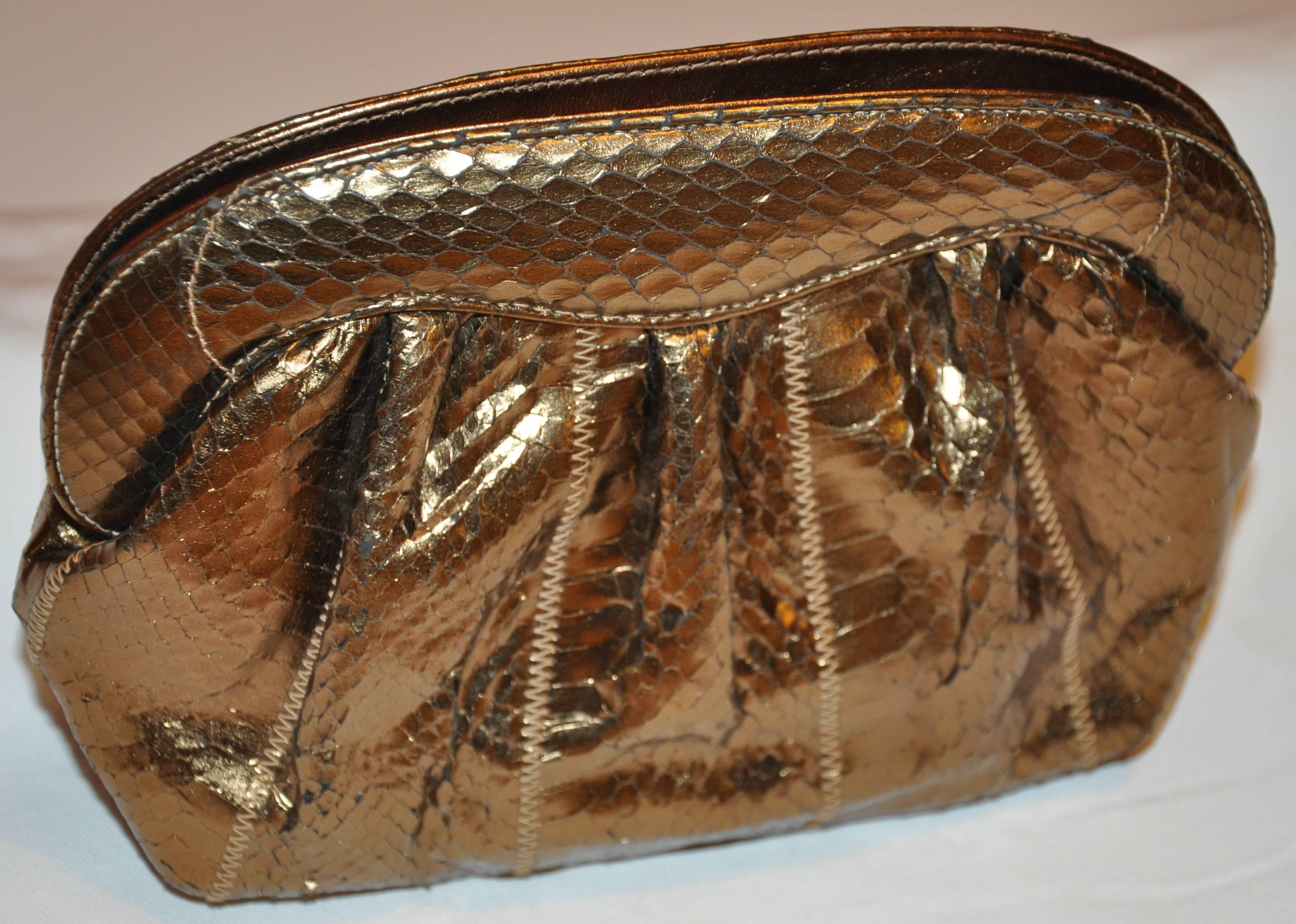        Meyers wonderfully elegant bronze pylon-skin clutch with the option to use as a shoulder bag is desired. The interior is lined with a warm tan silk. Top closure features a snap closing. The length across measures 9 inches. The height measures