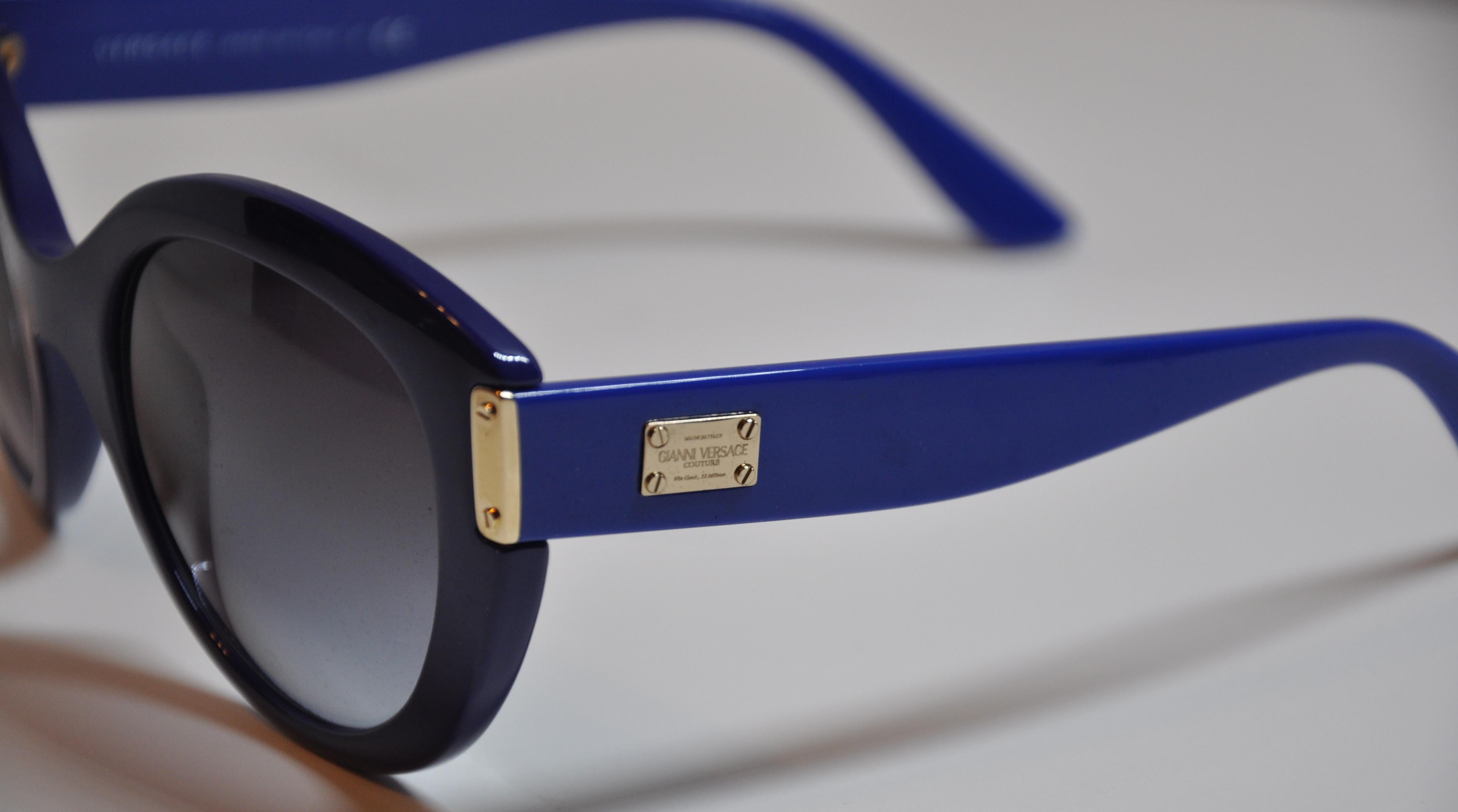        Gianni Versace wonderfully wicked thick bold Lapis-shade sunglasses accented with gilded gold hardware and studs. The arms are detailed with the signature name etched into the gilded gold hardware plate. The front measures 5 7/8 inches