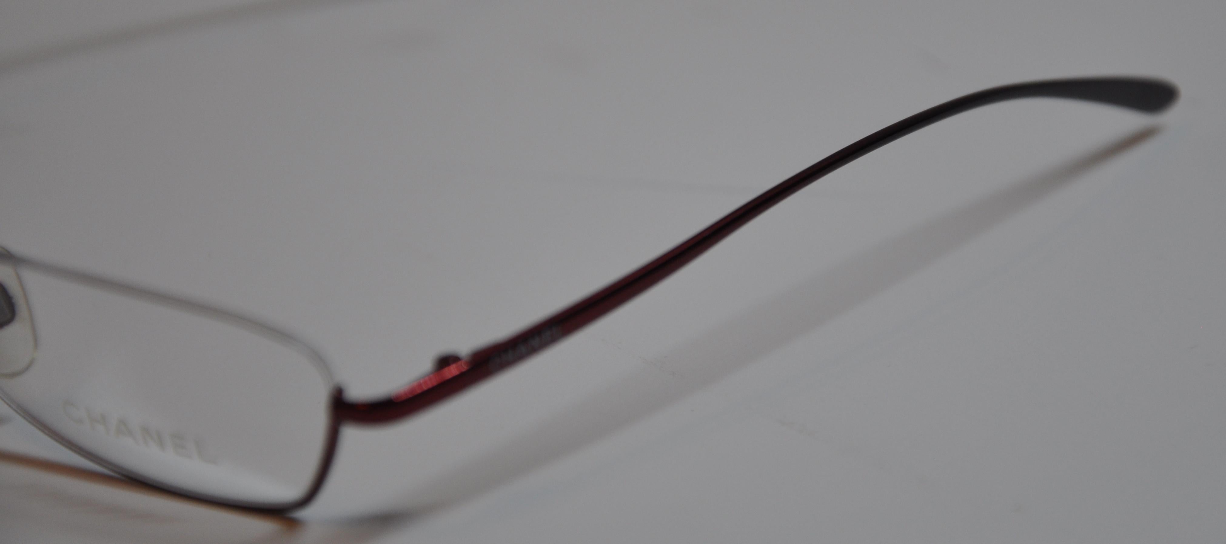        Chanel wonderfully elegant titanium iridescent cranberry weightless half-frame reading glasses are detailed with curved corners in front. The arms are nicely curved for a more comfortable fit. The front measures 5 1/2 inches across,  height