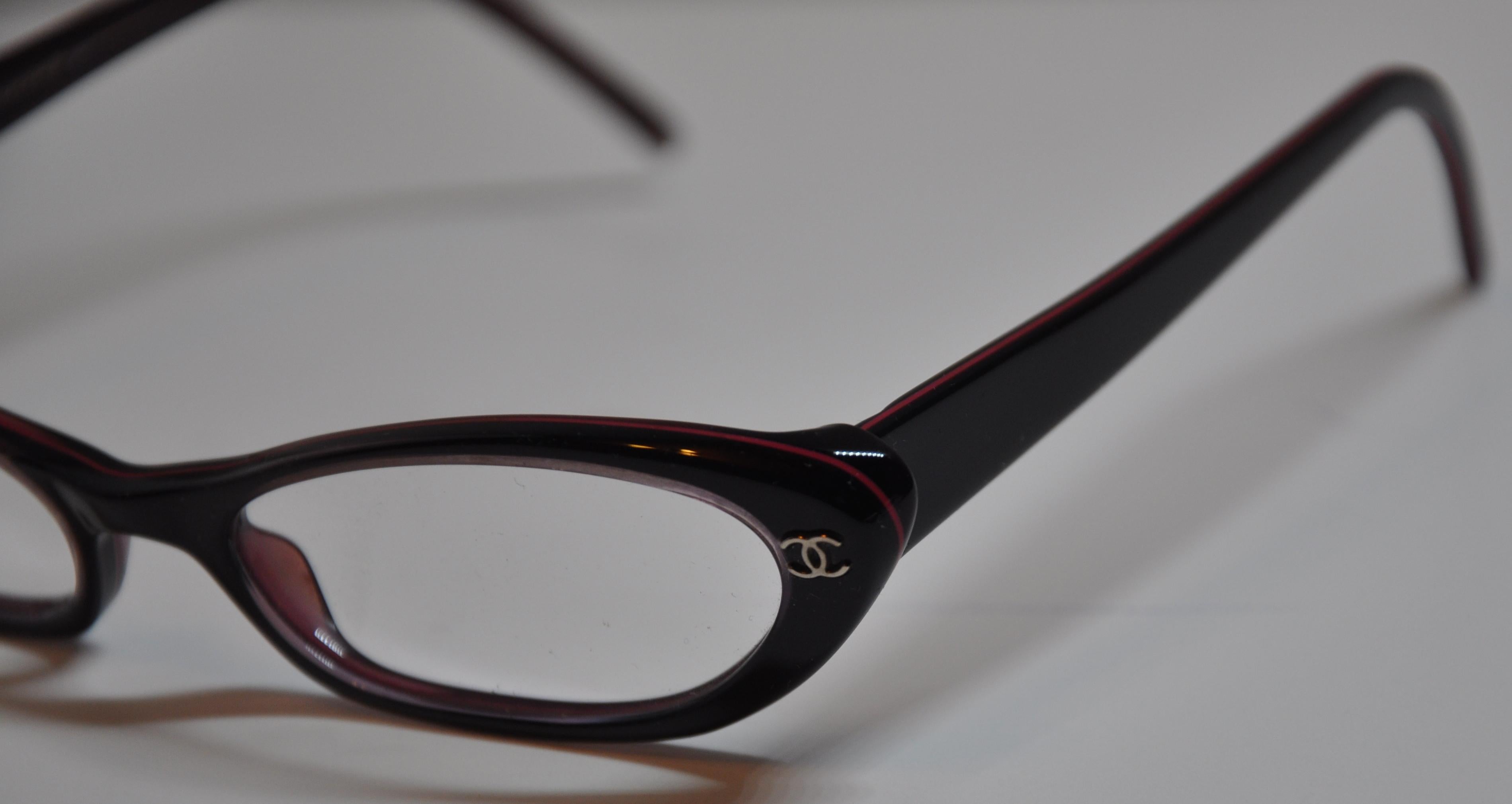        Chanel wonderfully elegant signature thick black lucite prescription glasses is accented with burgundy lucite interior as well as accents trimming on the frame's front.  The signature 