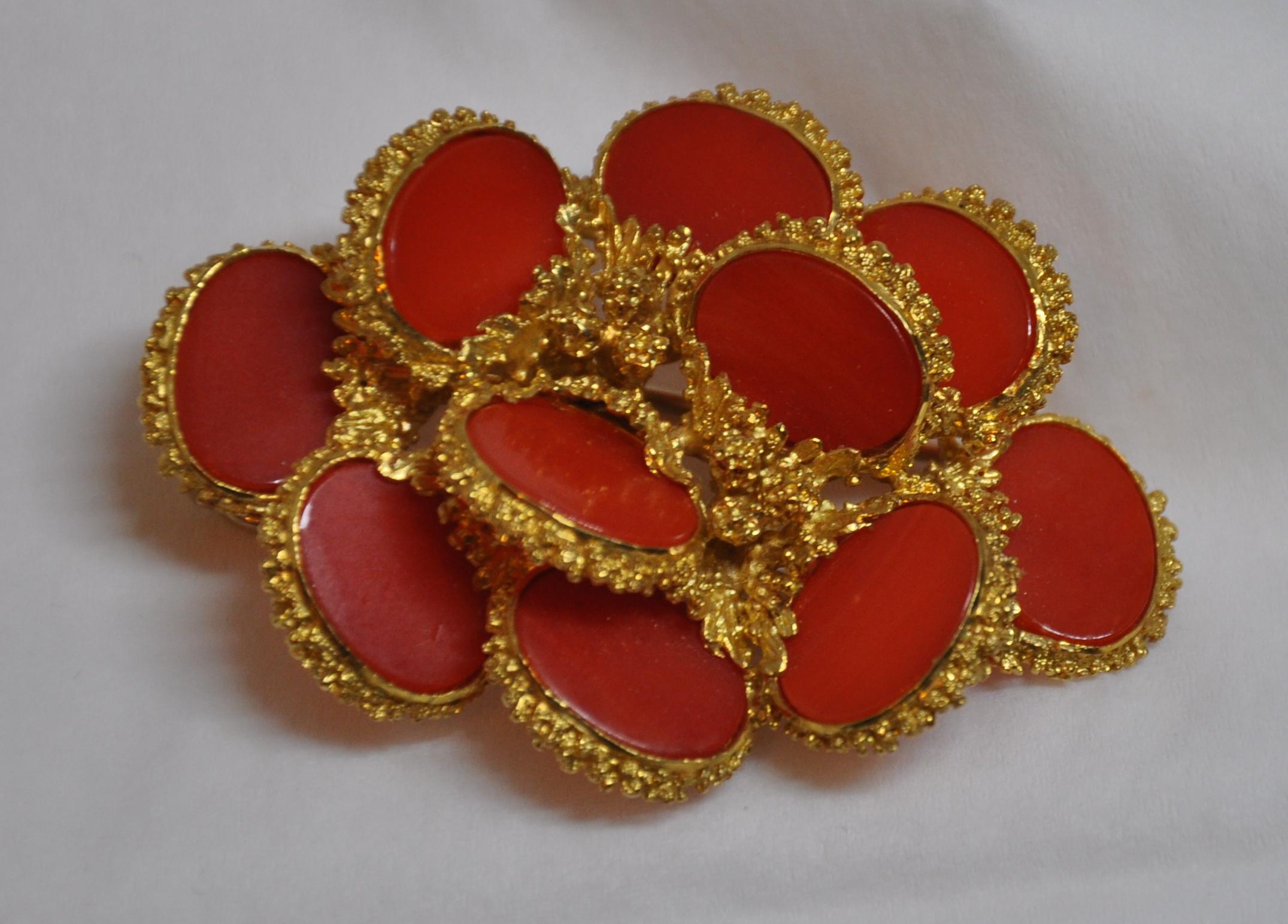        Wonderfully detailed etched 18k gilded yellow gold brooch and optional hat pin is accented with bursts of natural coral. The back is detailed with a safety pin to help secure this wonderfully elegant brooch in place. The brooch measures 2