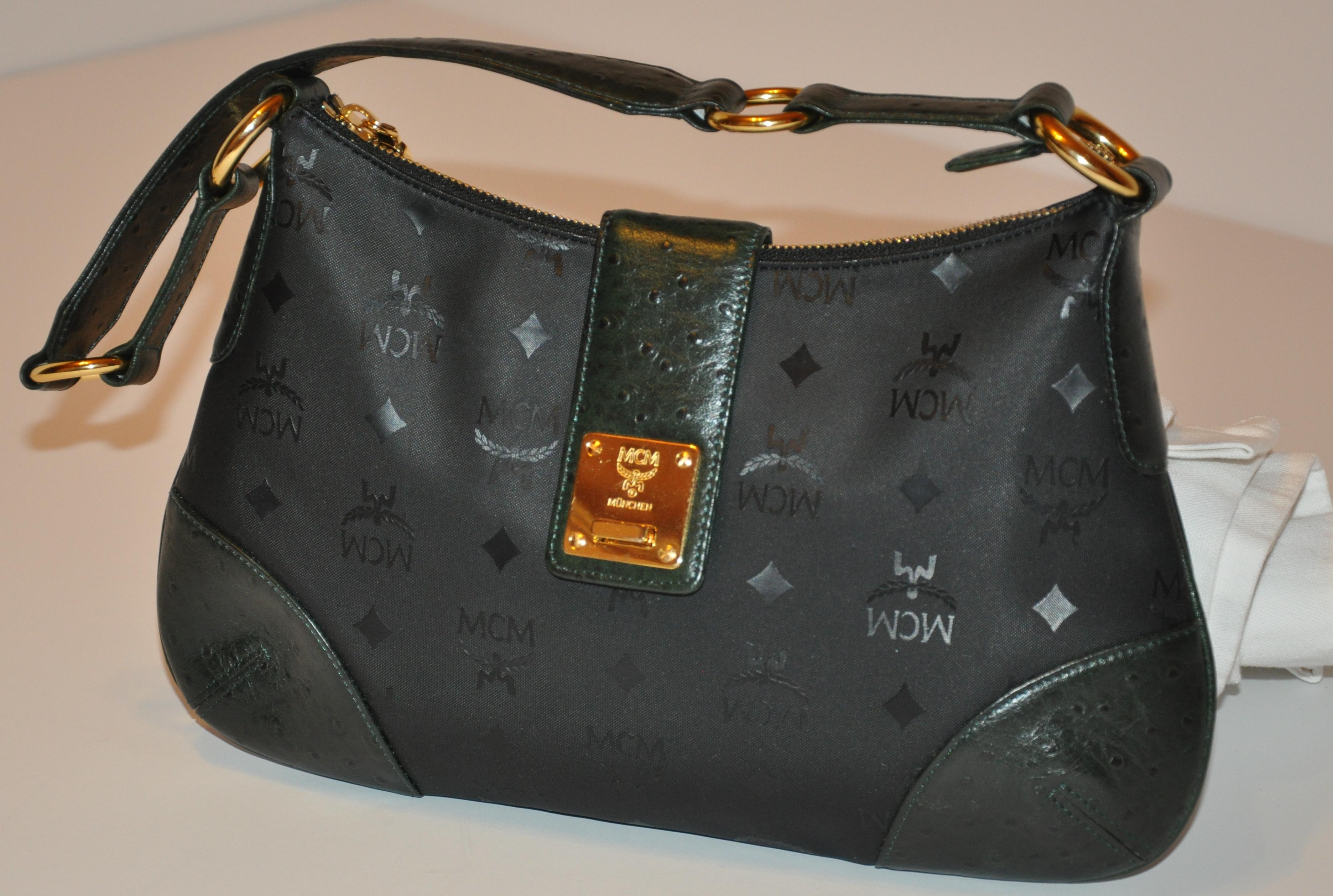        MCM wonderfully detailed black signature monogram shoulder bag accented with embossed forest green ostrich on the corners, top flap, side panels, tabs, and as well on the gilded gold hardware shoulder straps accents the gilded gold hardware.