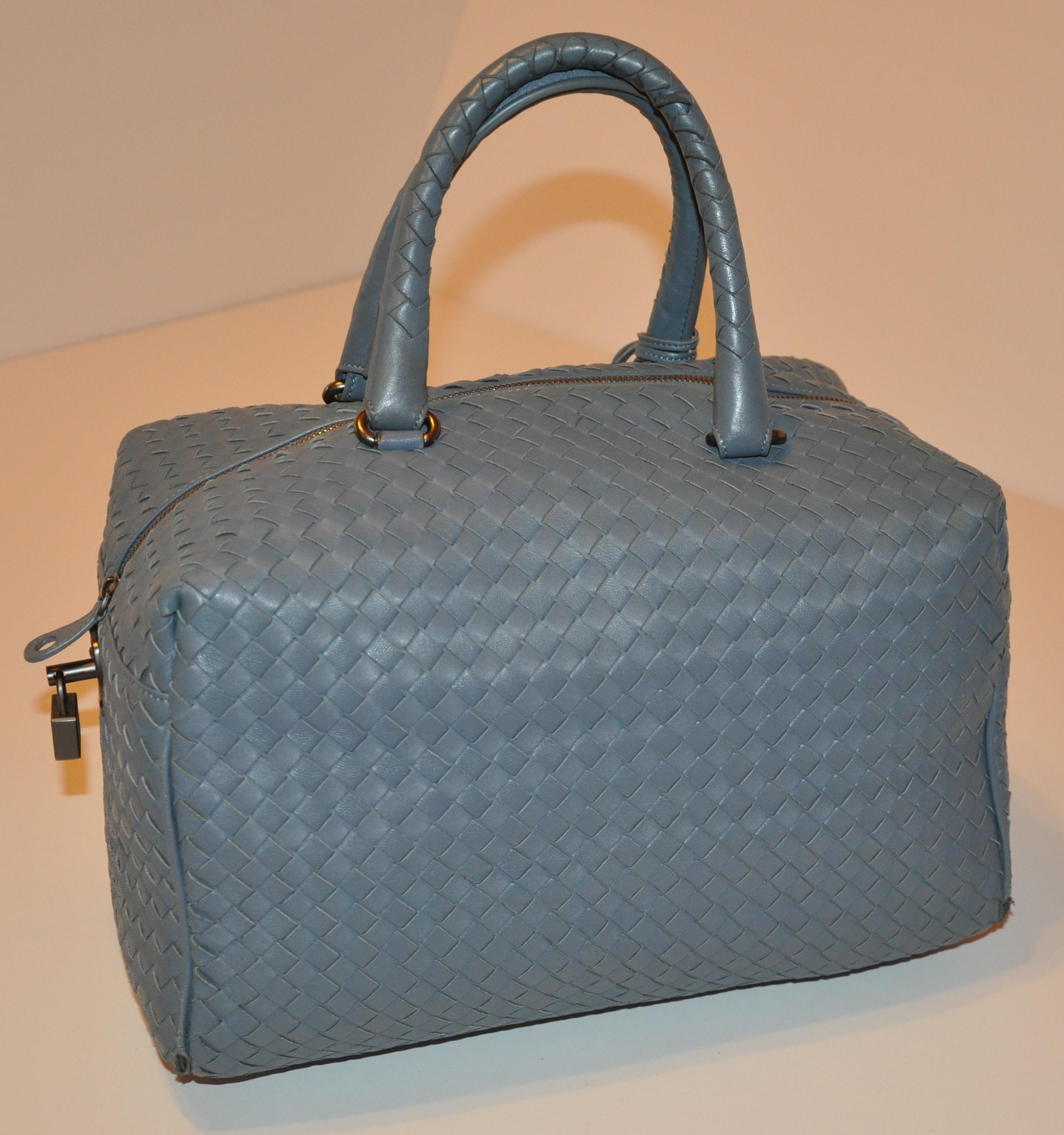        Bottega Veneta wonderfully soft steel-blue signature woven lambskin weekend tote is detailed with a zippered top which measures 16 inches. The double woven handles is accented with steel hardware and stands at 6 1/2 inches in height. The