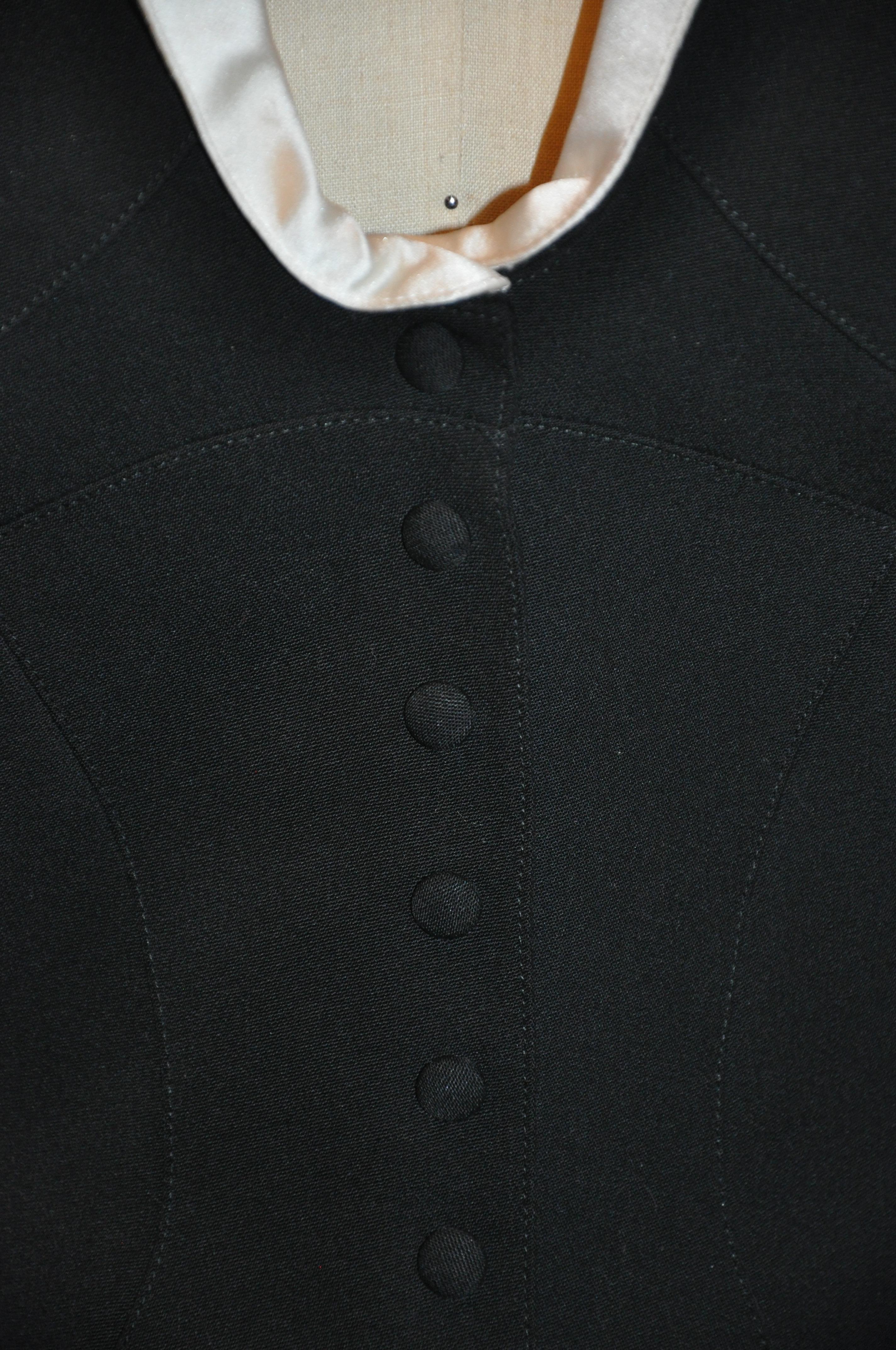      Thierry Mugler wonderfully detailed signature black wool accented with cream Silk -Satin sculpted smoking jacket has 8 black-covered snap button in front. Towards the hip as well as on the sleeve's cuffs are detailed sculpted curves. The
