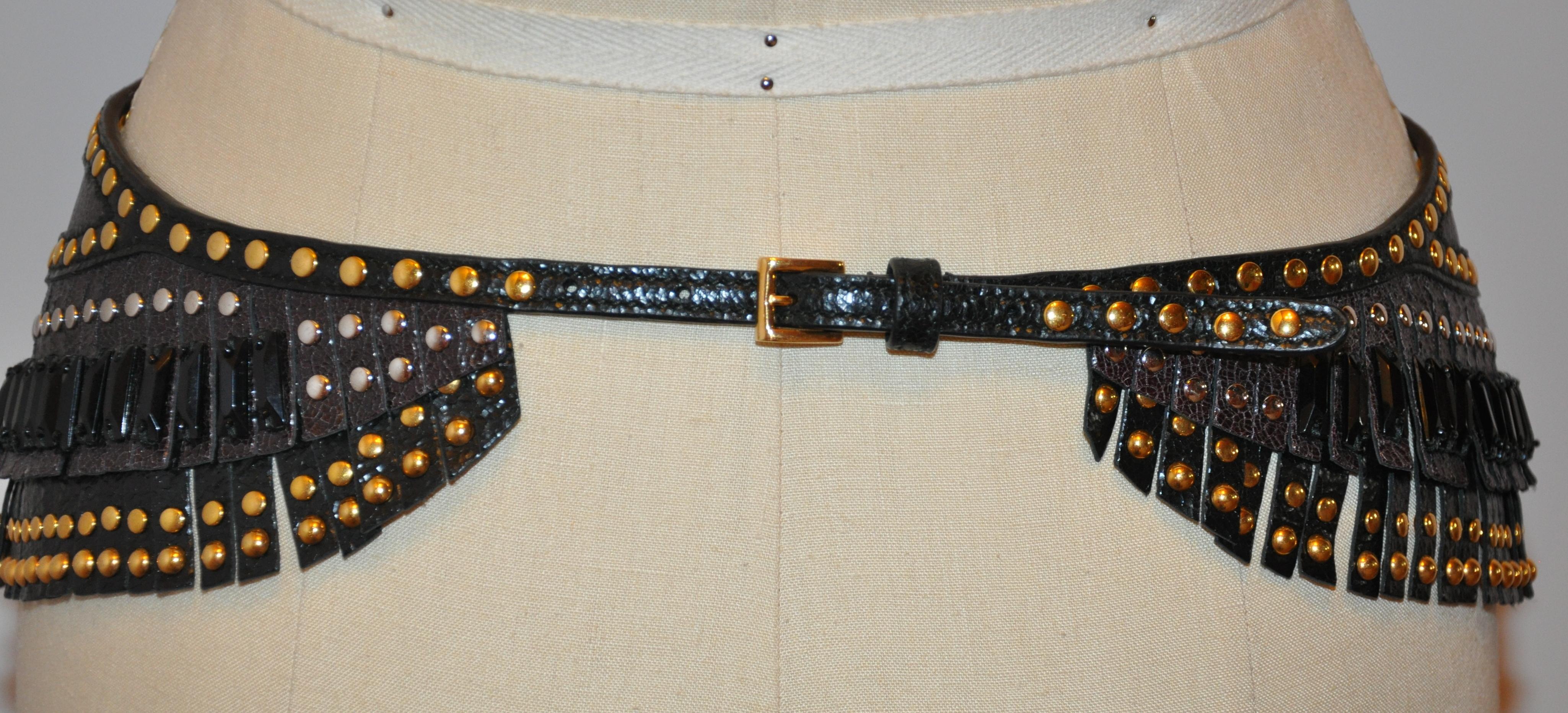        La ceinture à boucle frangée marron coco de Prada est ornée de plusieurs clous dorés sur toute la longueur, accentués par des perles oblongues noires à billes multiples. La taille mesure de 28 à 32 pouces selon votre ajustement le long des