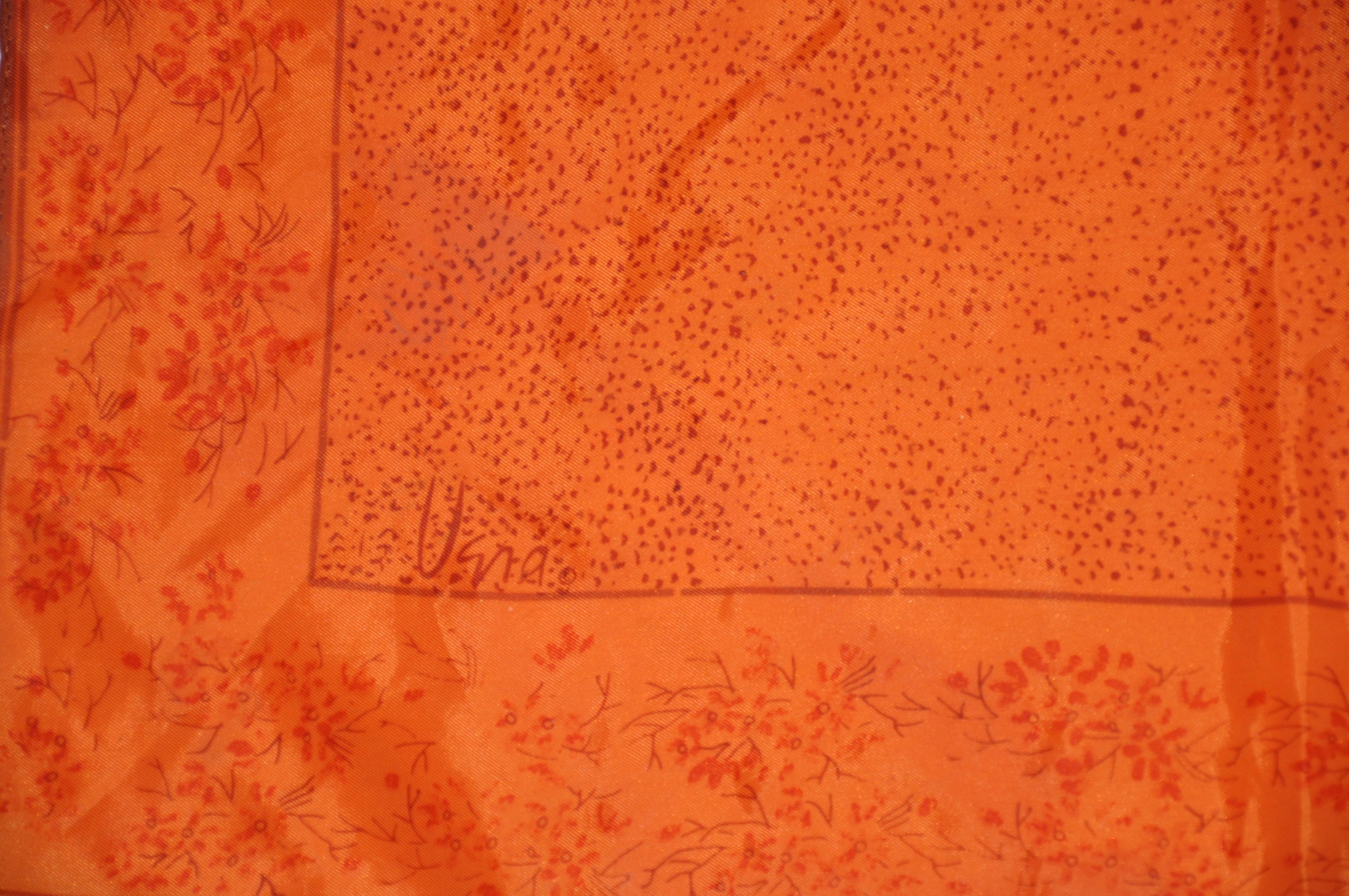        Le foulard en acétate Vera warm tangerine avec des bordures florales éparses mesure 22 pouces par 22 pouces. Fabriqué au Japon.