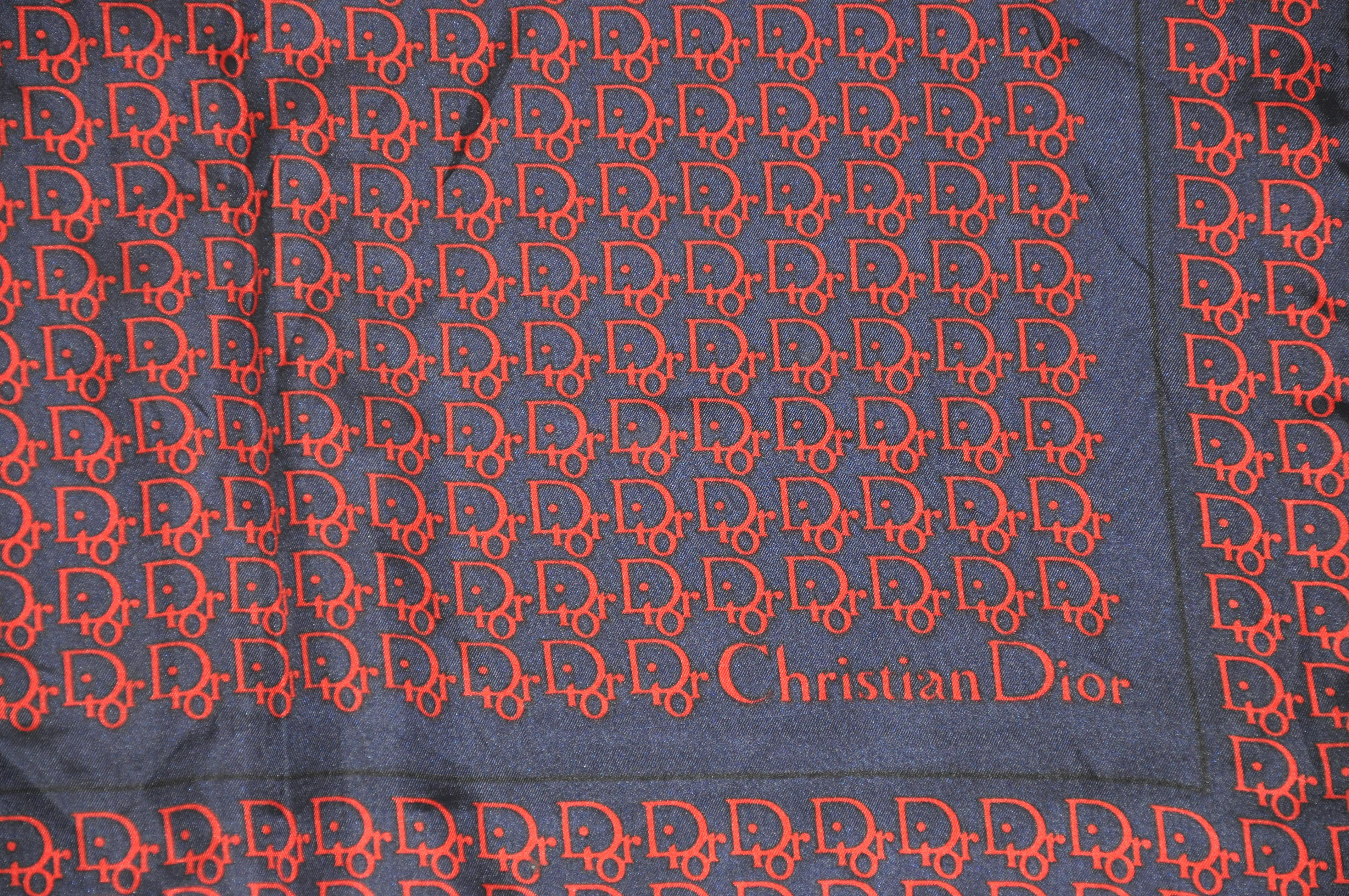        Christian Dior's signature monogram silk scarf in Midnight blue and red accented with hand-rolled edges and measures 19 inches by 19 inches. Made in Italy.