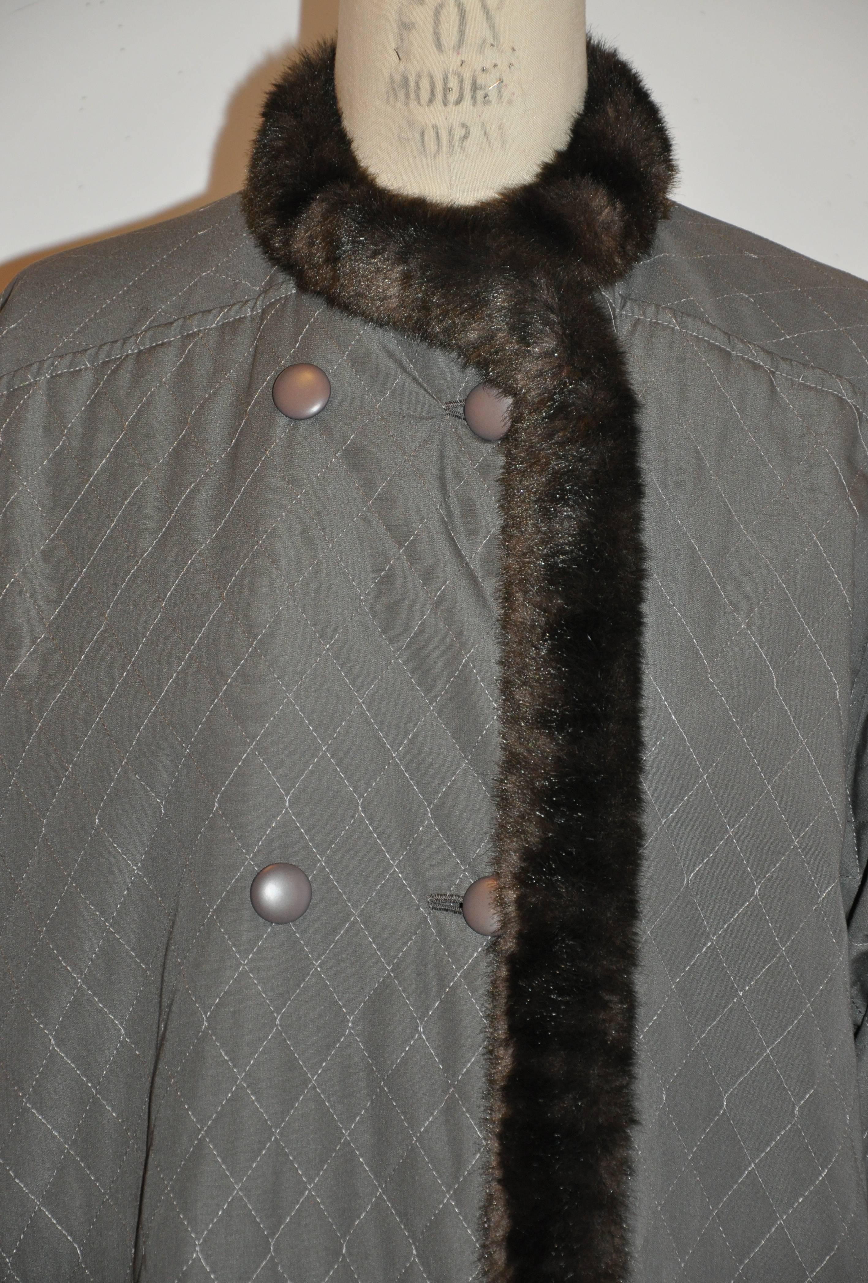            Givenchy's wonderfully detailed olive green quilted flared coat is feather-lightweight, accented with faux fur in coco-brown appearing to be mink in appearance. The double-breasted from is actually single breasted with two deep set-in