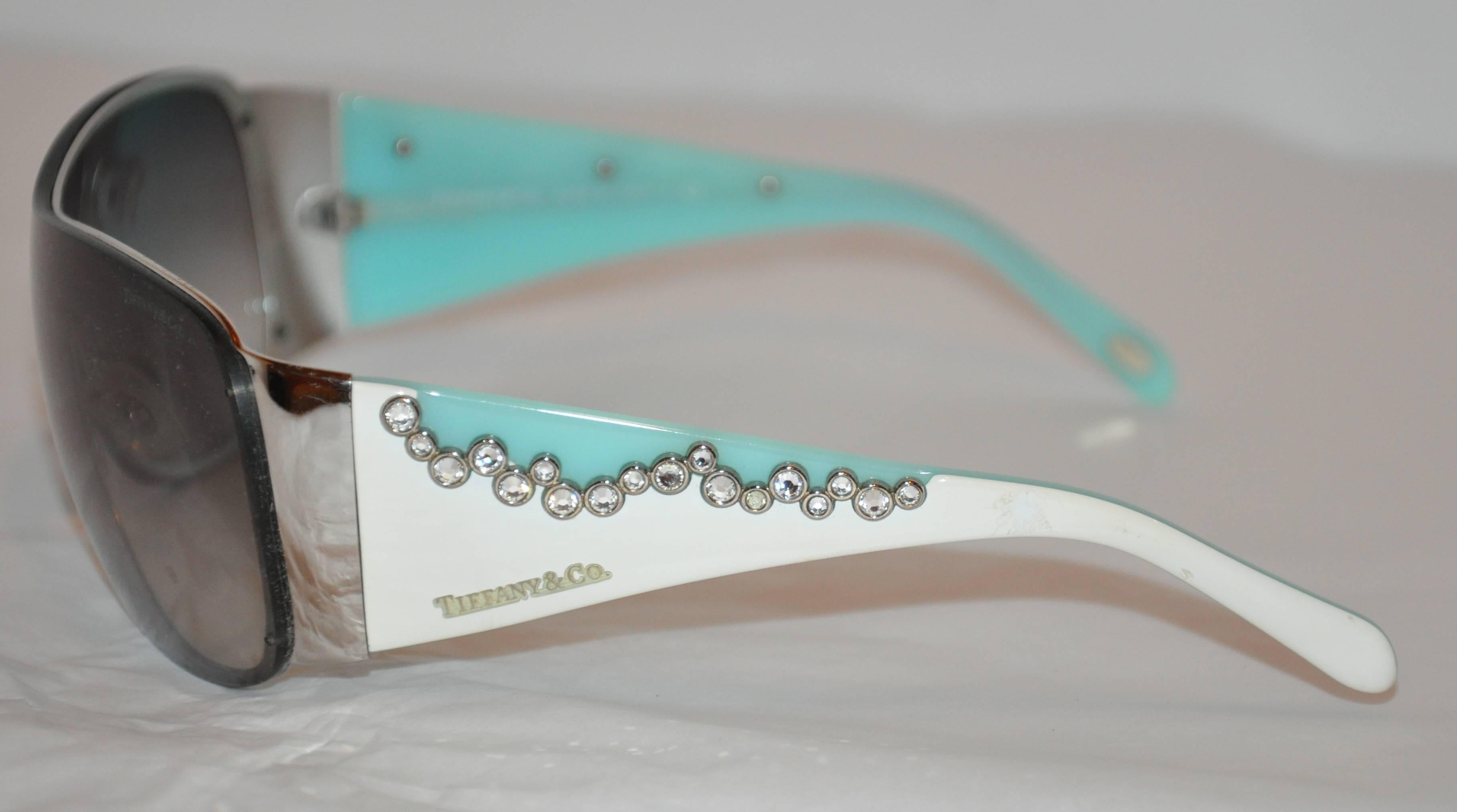           Tiffany & Co. thick lucite in their signature turquoise shade combined with white lucite and accented with detailed multi-rhinestones set in silver hardware settings on both arms of these wonderful sunglasses. The front measures 5 1/2