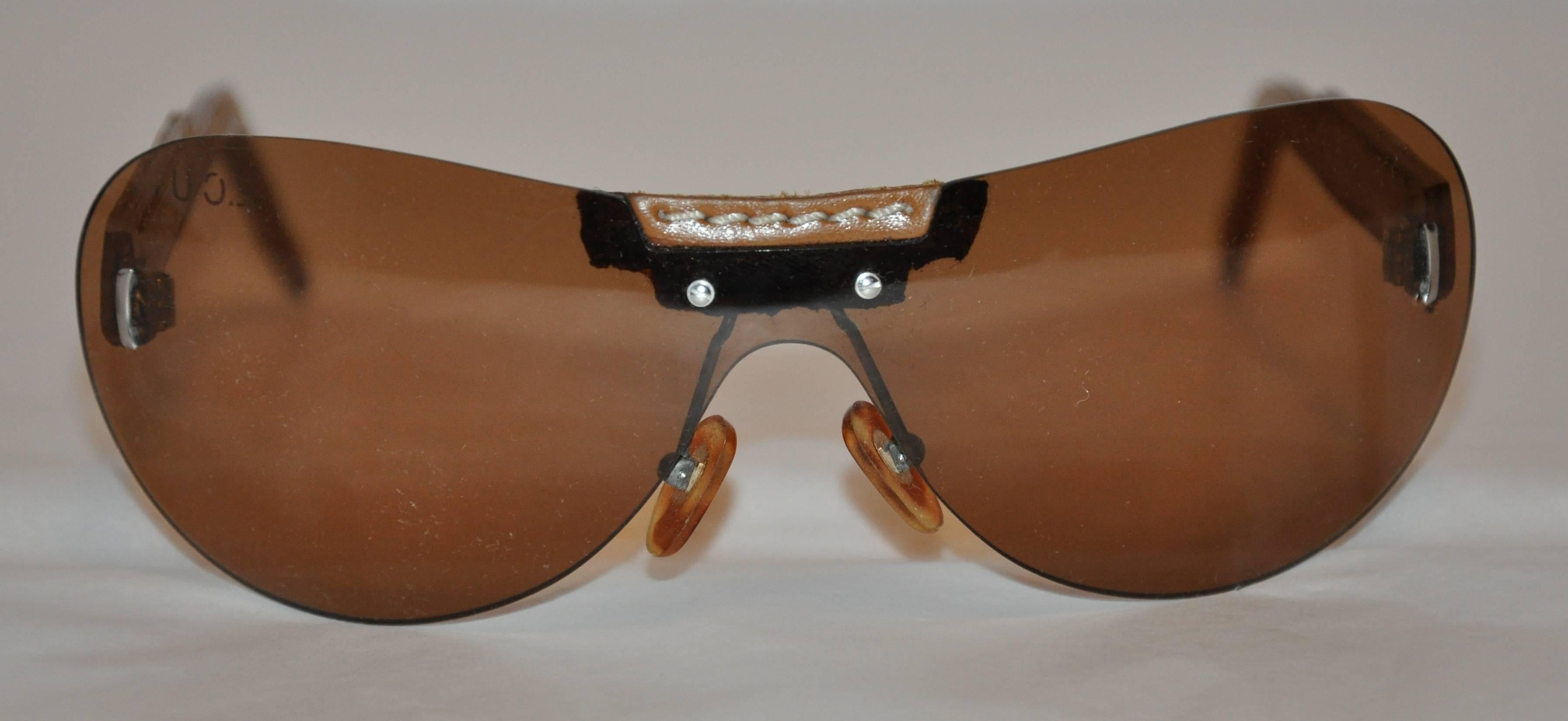           Louis Vuitton sunglasses are detailed with hand-stitched tan leather arms. The front measures 5 5/8