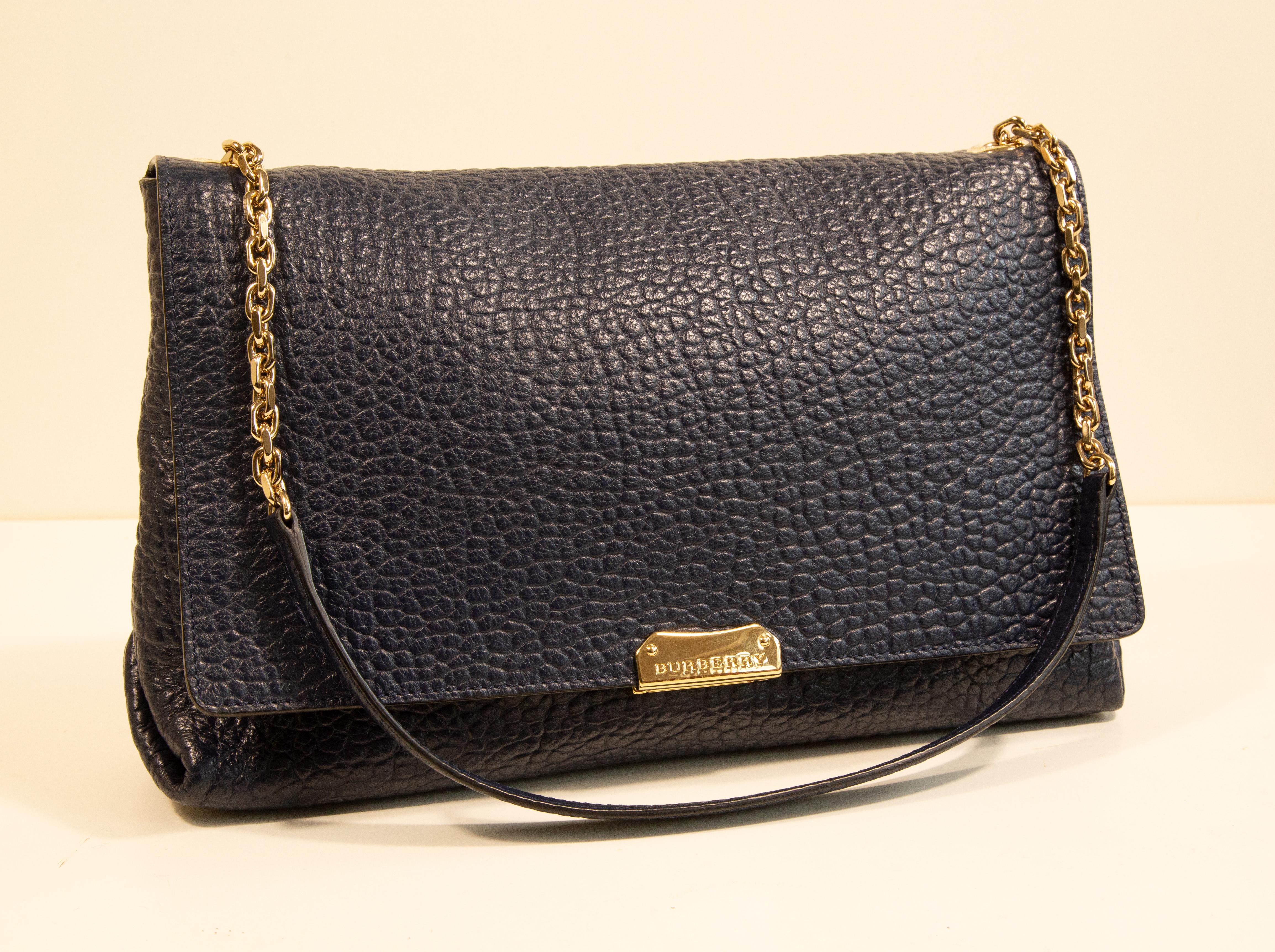 Sac à bandoulière Burberry en cuir texturé bleu marine avec accessoires dorés. L'intérieur est doublé de tissu noir et de cuir bleu marine, et à côté du compartiment principal, il comporte trois poches dont l'une est dotée d'une fermeture éclair. Le