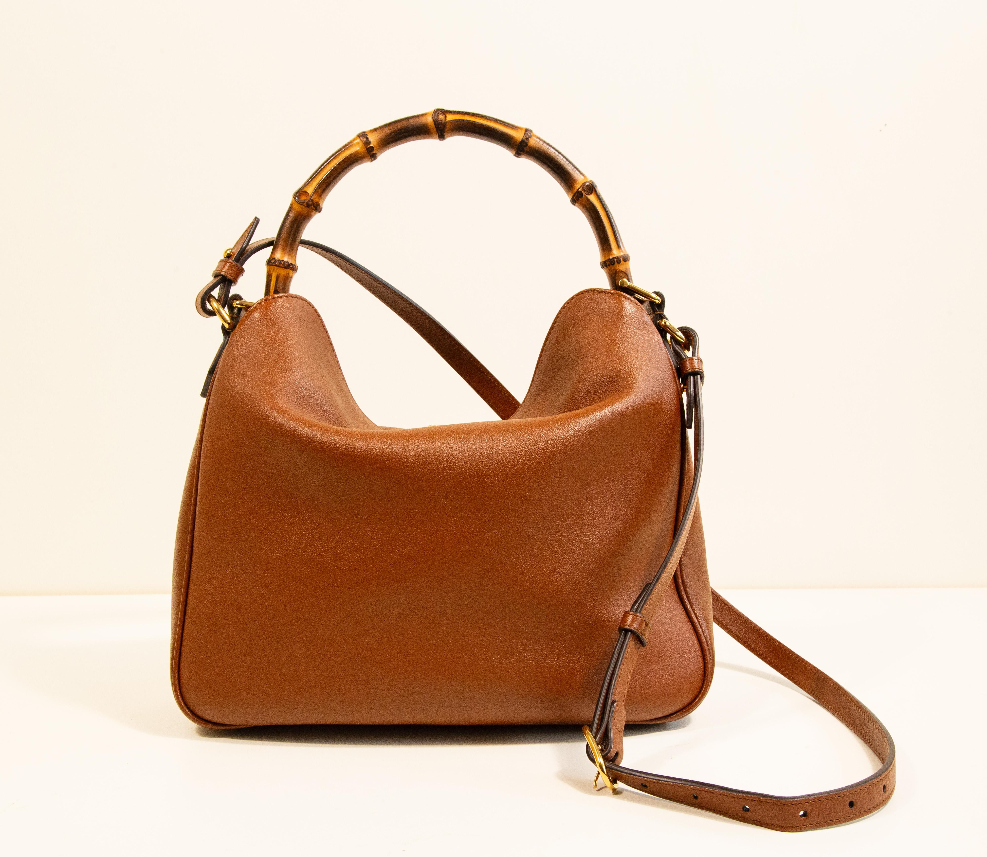 Sac à bandoulière Gucci Diana Medium en cuir marron avec accessoires dorés. Le sac est doublé de daim beige et, à côté du compartiment principal, il comporte une poche latérale zippée. La bandoulière est détachable et réglable (longueur maximale 107