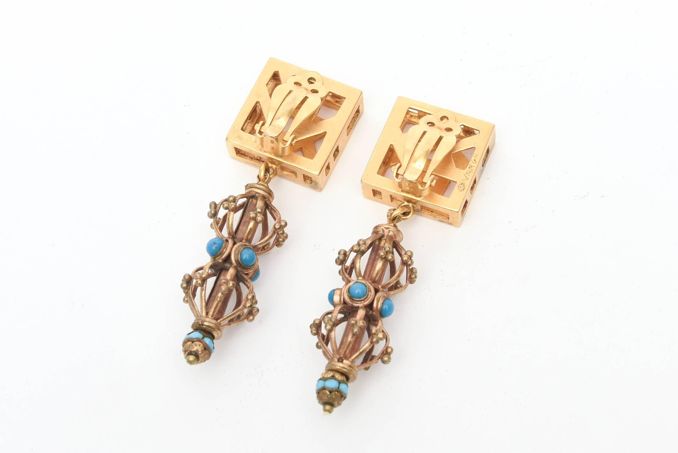 These unusual pair of clip on earrings have a number of great components going on. They are signed Varga . Gilt toned metal meets turquoise colored glass in the cage like form. They are sculptural and look great on! They look as if they were just