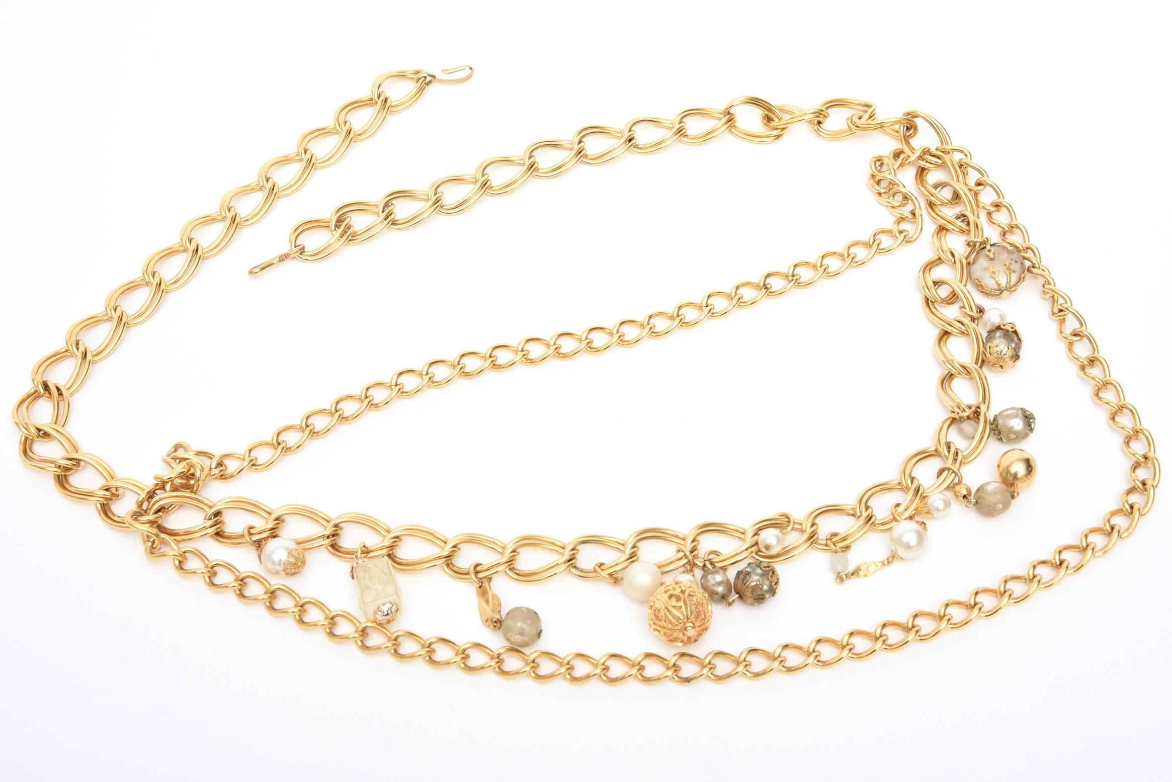 This vintage gold plated fabulous and chic chain link belt with faux pearls and small pendants dangles with a v form of chains of a 4 inch drop with the pendants hanging in the middle. The chain links are 2 different sizes. It is from the 70's.