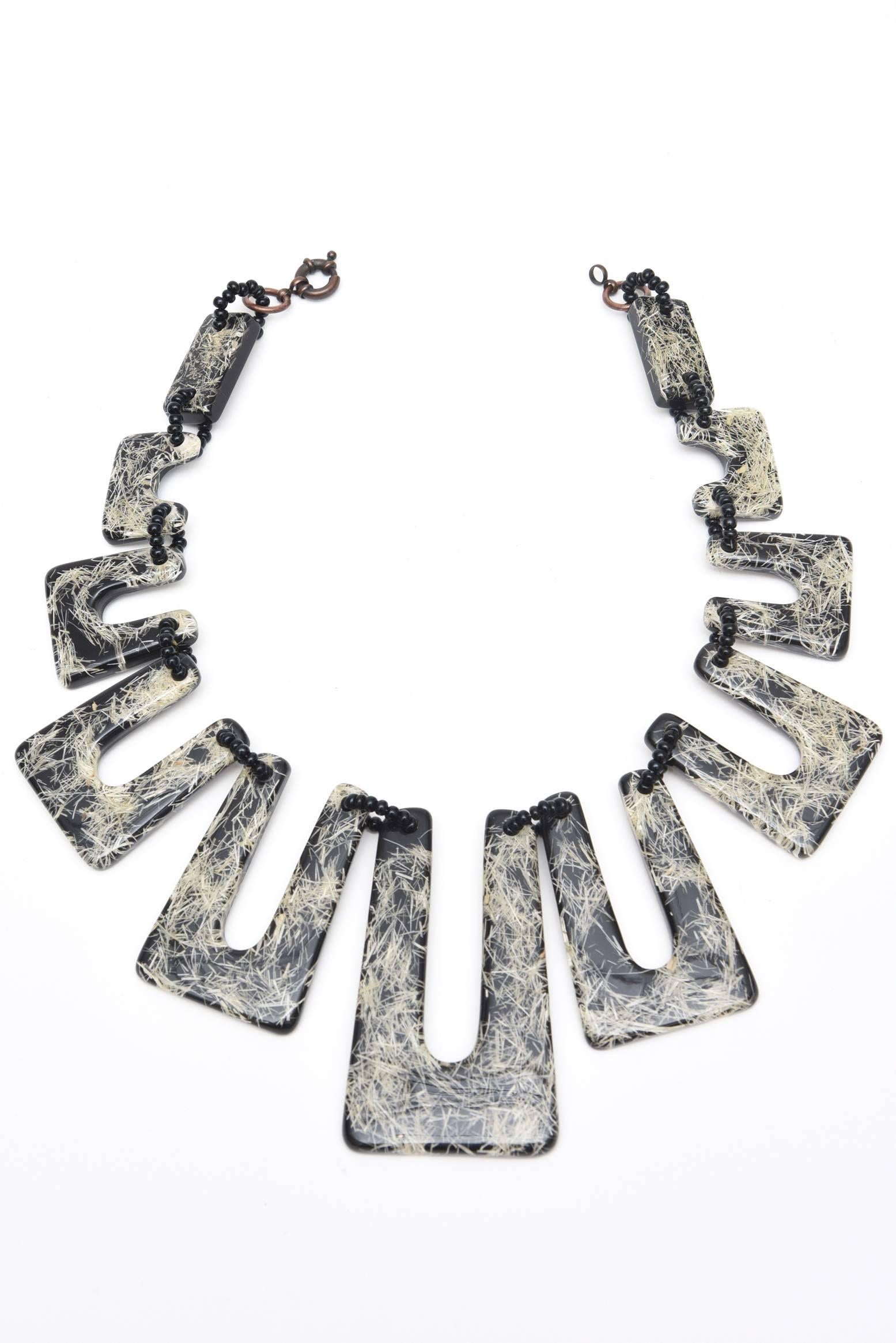 The graphic and painterly black and white resin french necklace of 9 graduated inverted U's has inspirations from the renowned and collectable painter: Jackson Pollack. This is artful and dramatic and looks great against all colors. There are small