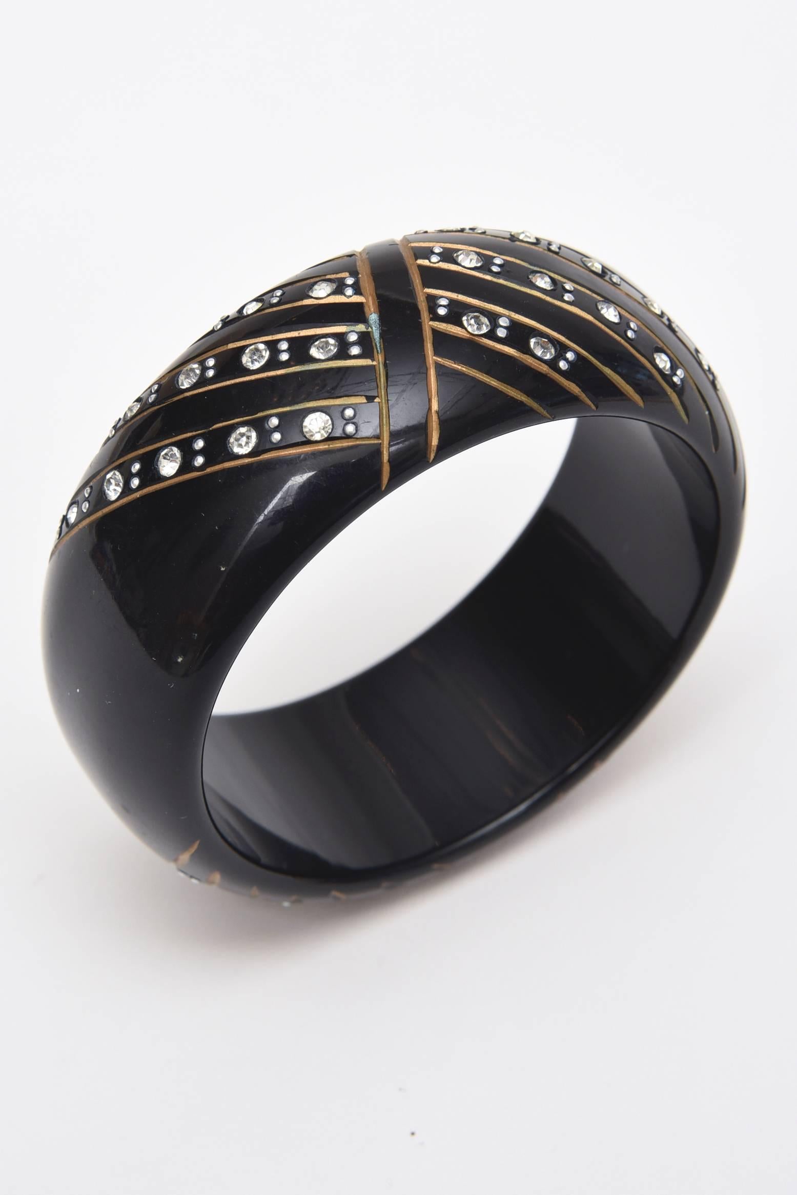 This art deco inspired design of this french resin and rhinestone thick bangle bracelet is timeless and dramatic. It is modern yet resides in a time past.
It is from the 80's. It is wider than most for these resin bracelets.
