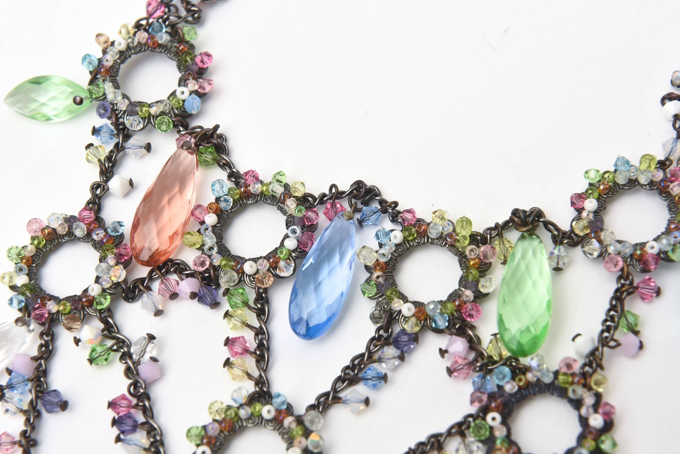 This stunning multi colored glass Austrian swarovski crystal collar bib necklace is set against a dark metal frame. It is signed Erickson Beamon. The intricate work of this layered and cascading collar bib necklace is so perfect for any season set