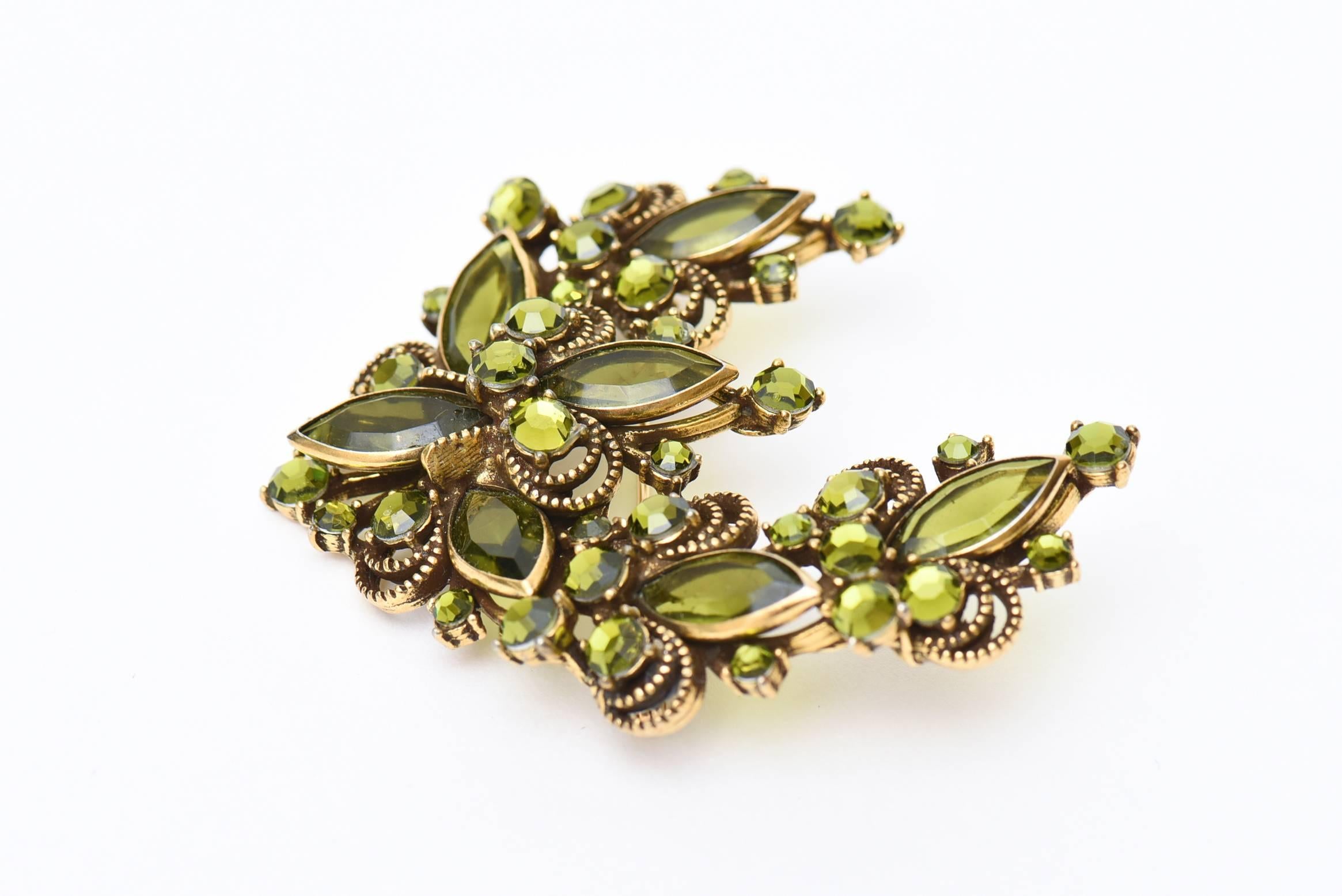 This mid century 50's vintage pin or brooch is signed Weiss. The chartreuse green color is beautiful of the glass rhinestones  and is set well against the metal that has some decorative quality of braid like form. The half moon shape can work all