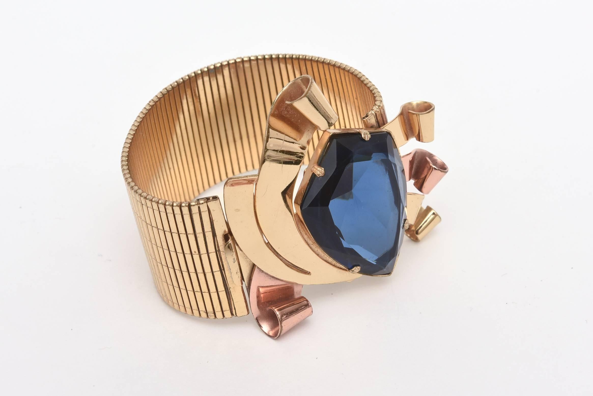 This fabulous retro cuff bracelet looks real! The brilliant blue faceted glass stone is vibrant and center stage. The combination of the two toned metals of ribbed gold plated and copper add to the theatrics of this unusual bracelet that is signed