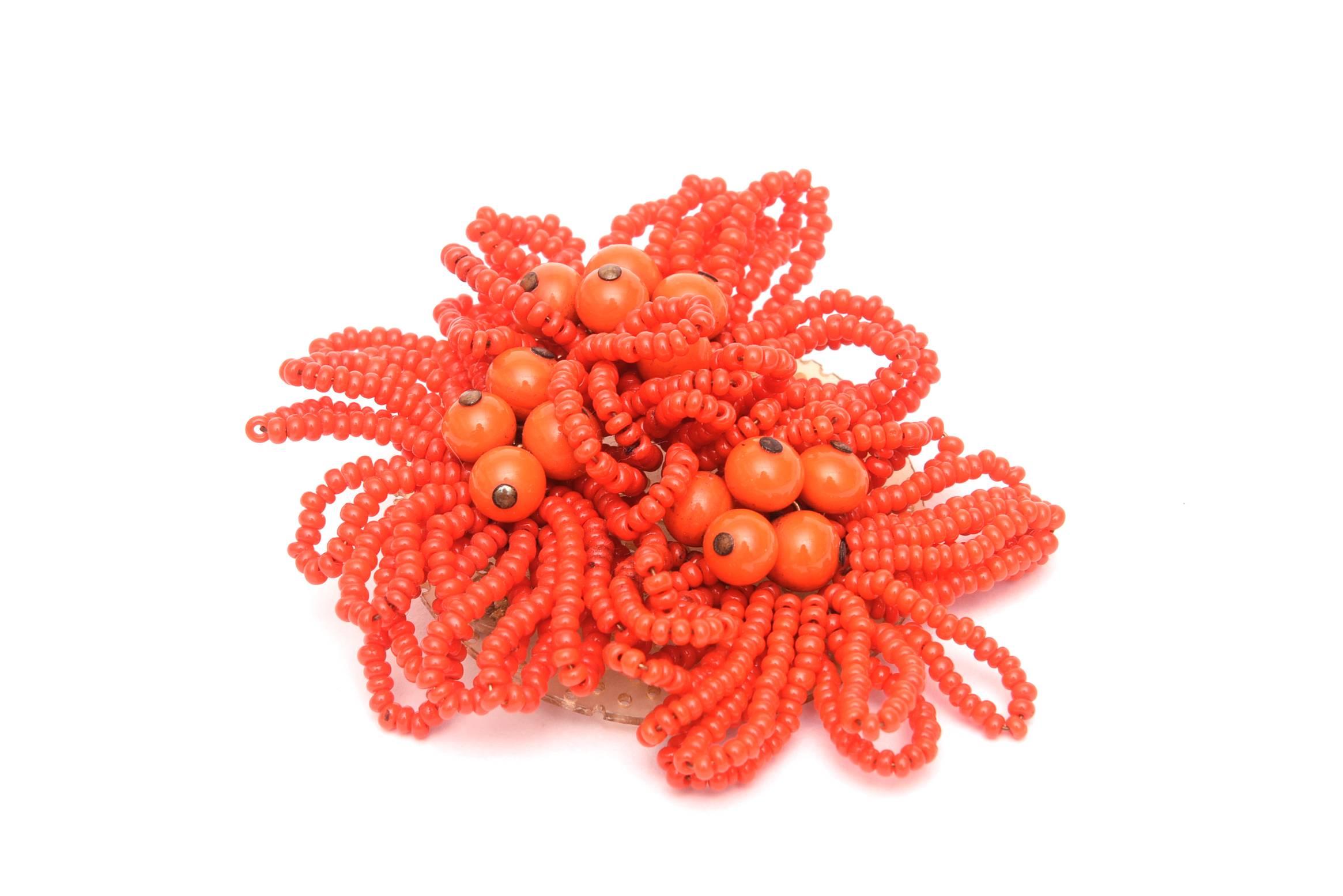 This unsigned vintage Miriam Haskell pin has the lovely color of orange beads in flower like sculptural form.There are larger beads with silver tips amongst the cluster. This is not a common piece by Haskell. It is 3.25