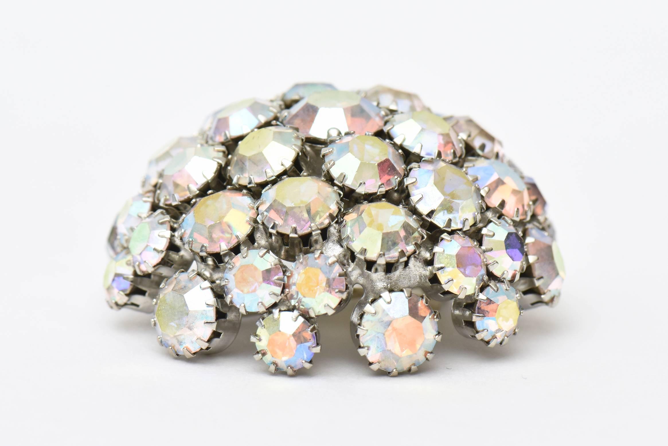 This glistening mid century pin/ brooch is made of gorgeous bora aurealis crystals. It changes color with the play of light and angle. It is signed Warner and prong set. It is dome shaped and will make any ensemble for day or evening sparkle. The